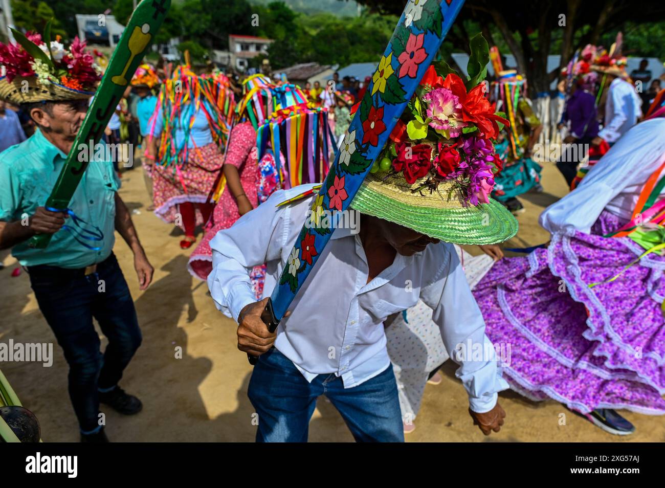 Au début de la célébration du Corpus Christi à Atánquez, département de Cesar, Colombie, les groupes de Negritos y Las Negritas dansent joyeusement sur la Plaza del Coco. Las Negritas portent des robes colorées, des coiffes élaborées, tandis que les Negritos portent des chapeaux et des épées en bois, ajoutant un élément dynamique et festif au patrimoine culturel dynamique de la communauté Kankuamo. Banque D'Images