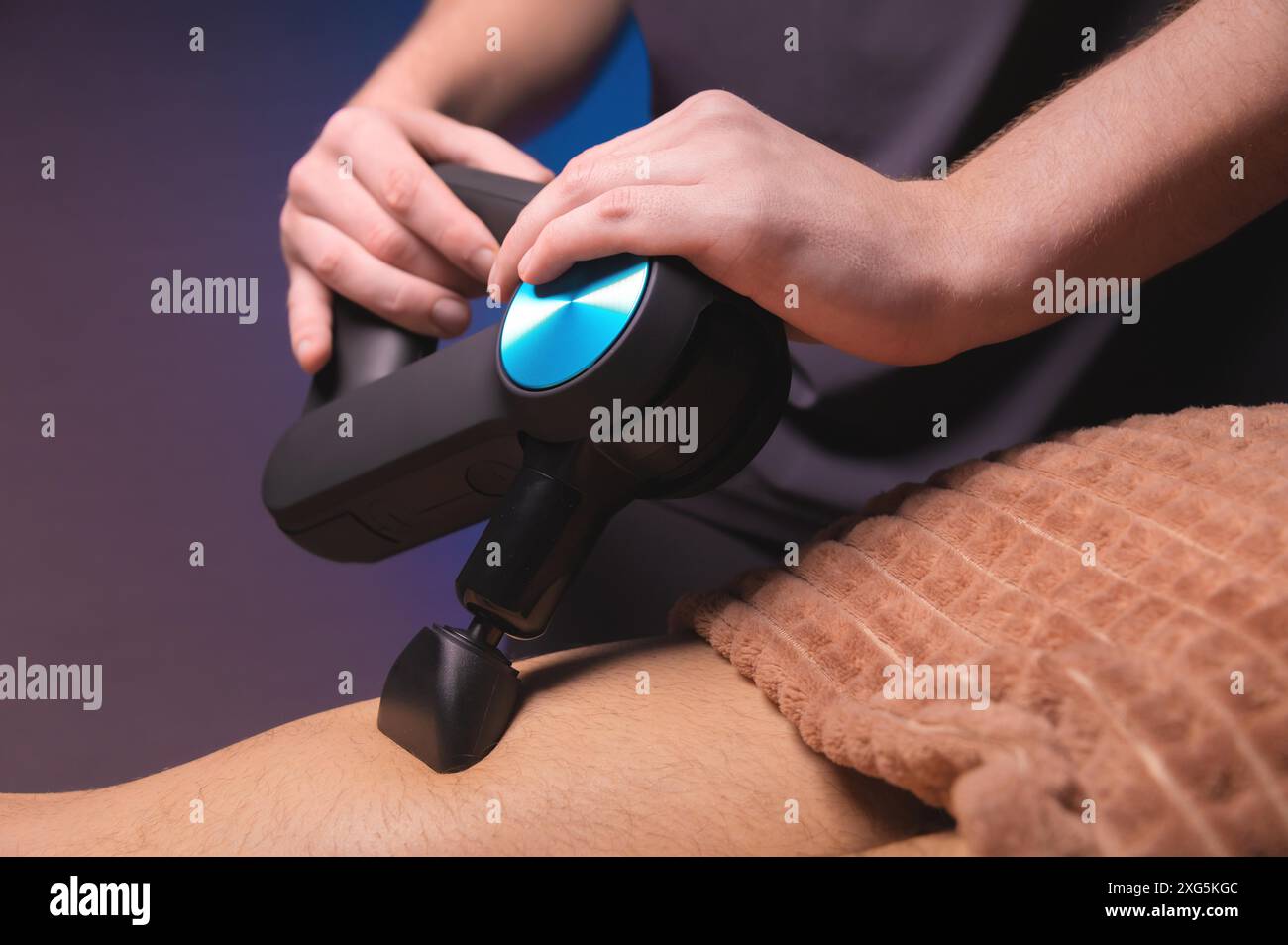 Massage professionnel avec un masseur de dos à percussion pour un homme. Travailler comme masseur à percussion Banque D'Images