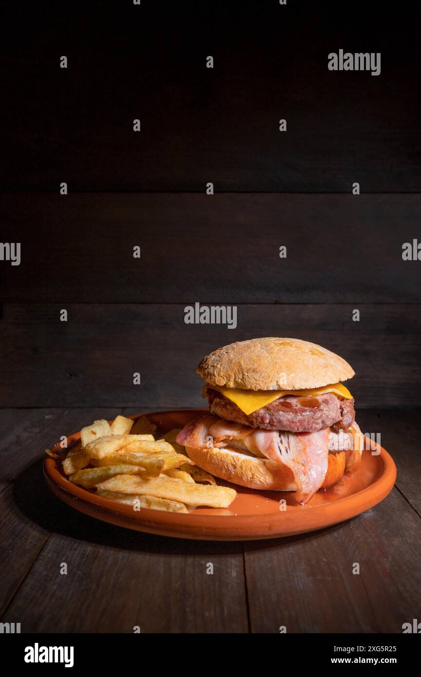 Hamburger de bœuf grillé de qualité supérieure avec bacon, fromage et frites. Délicieux hamburger américain sur fond de bois. Photographie de haute qualité Banque D'Images