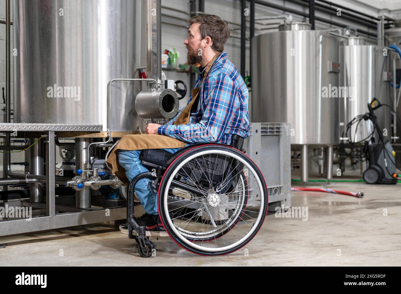 Homme en chaise roulante travaillant dans l'usine de brasserie. Photographie de haute qualité Banque D'Images