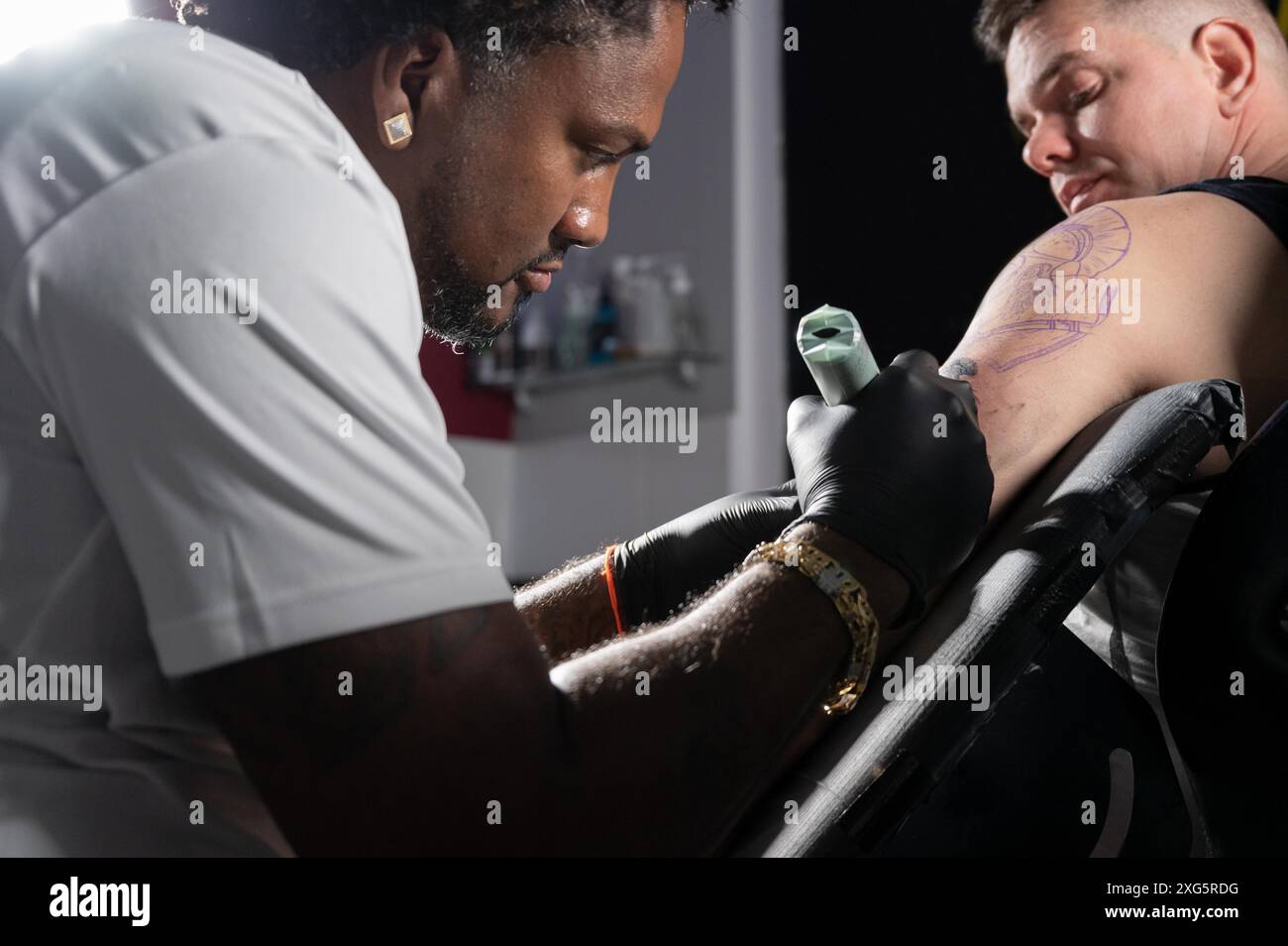 Tatoueur afro-américain professionnel fait un tatouage sur le bras du client. Photographie de haute qualité Banque D'Images