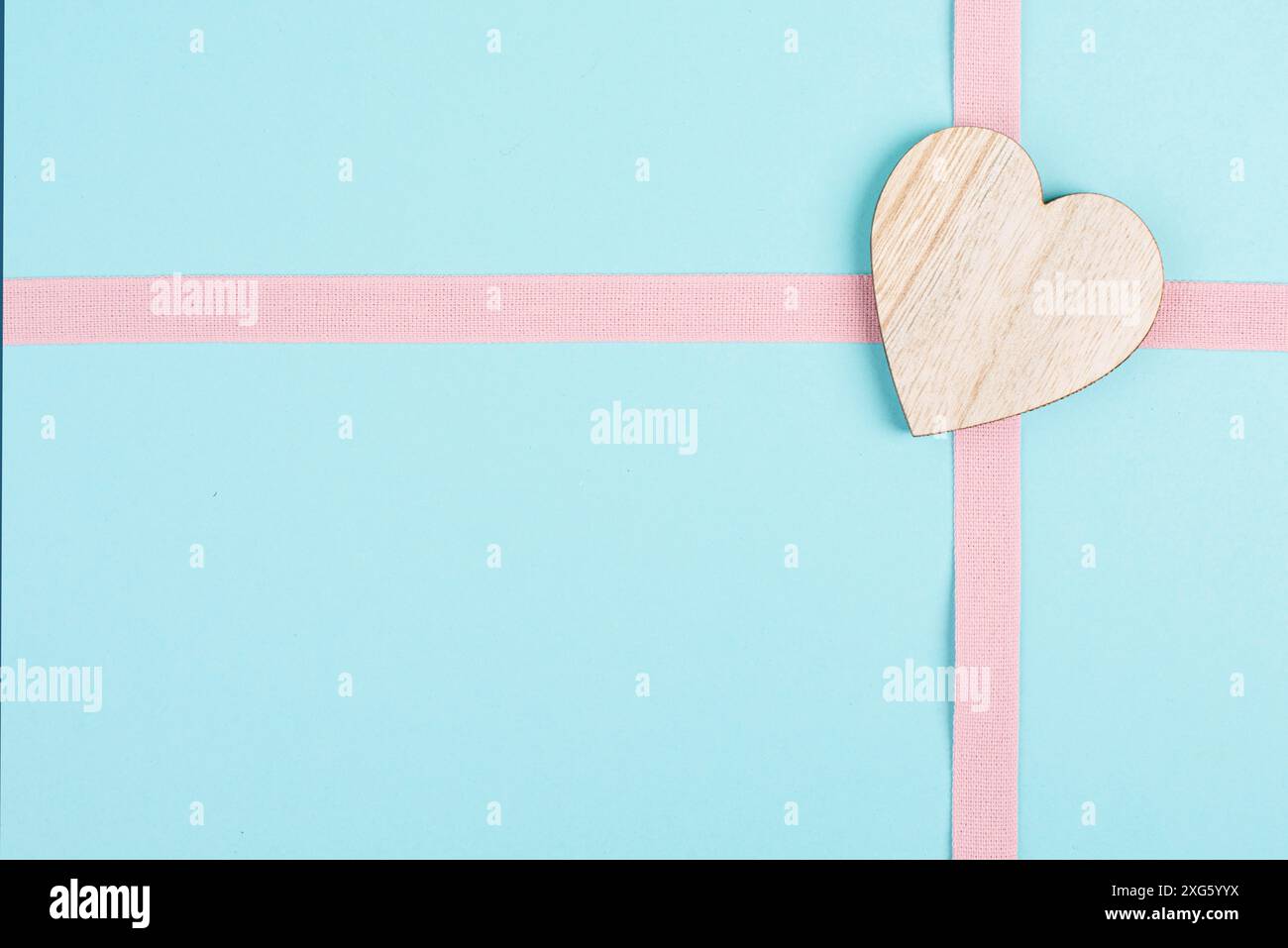 Coeur en bois sur fond rose et bleu clair, fond de vacances, jour de la Saint Valentin, symbole de l'amitié, de l'amour et de la charité Banque D'Images