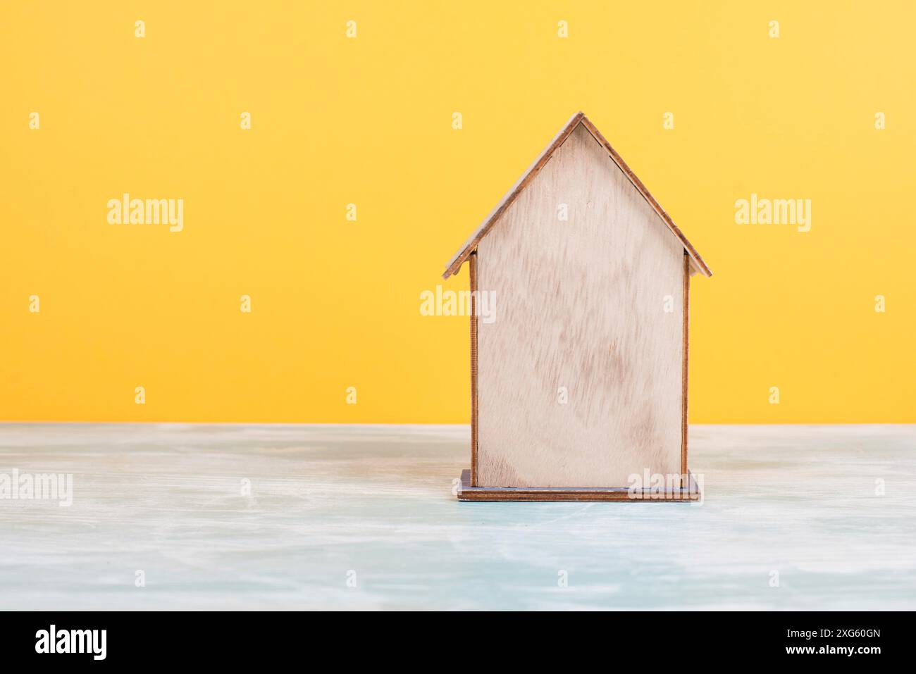 Maison en bois, fond jaune, achat ou location d'une maison, concept immobilier, réservation de maison pour les vacances, espace de copie pour le texte Banque D'Images