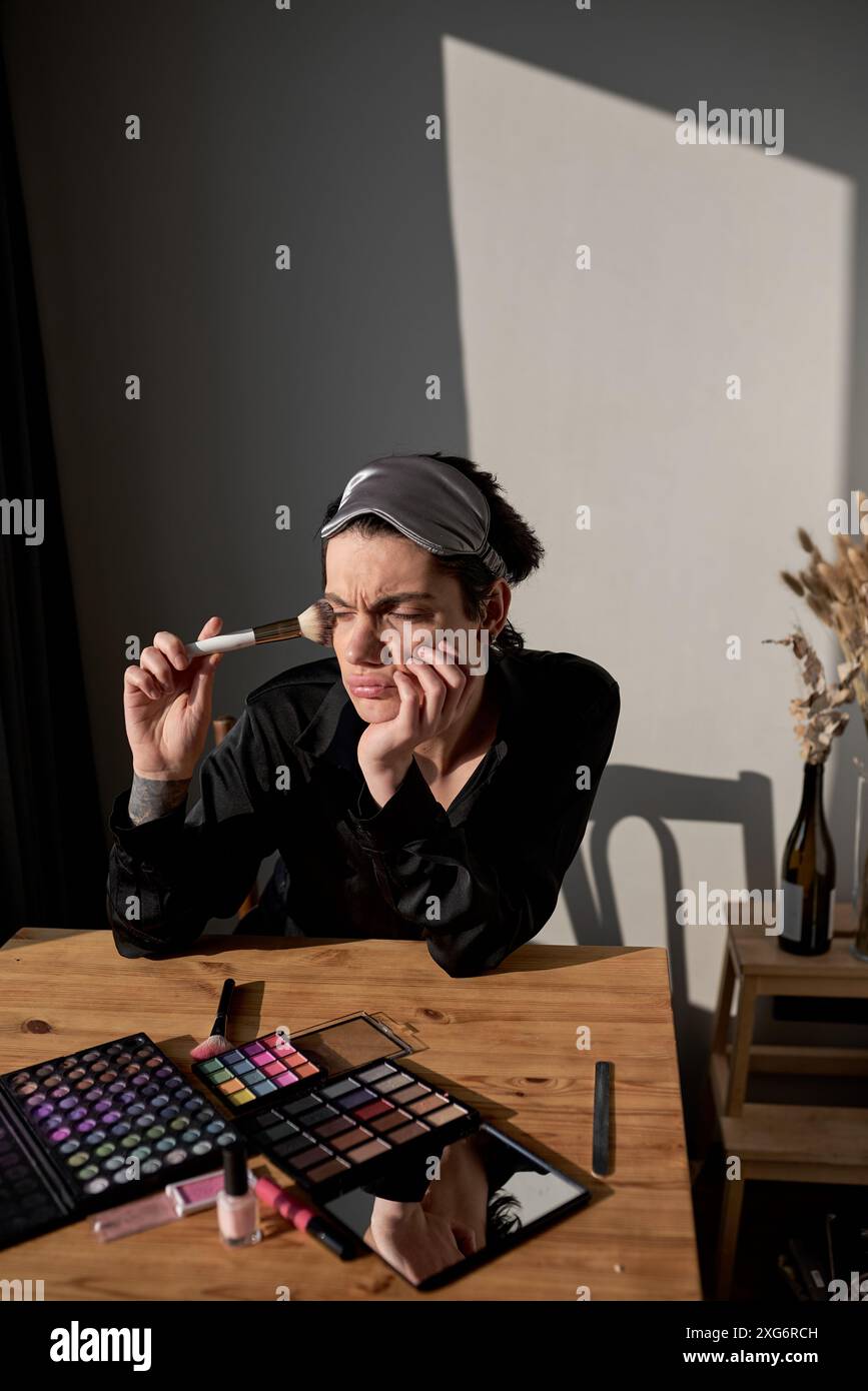 Portrait d'un jeune transgenre en robe noire appuyé sur son coude assis avec la main sur sa joue regardant de côté, portrait en gros plan. emotopn négatif Banque D'Images