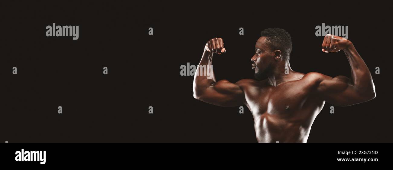 Homme musclé Flexing biceps sur fond noir Banque D'Images