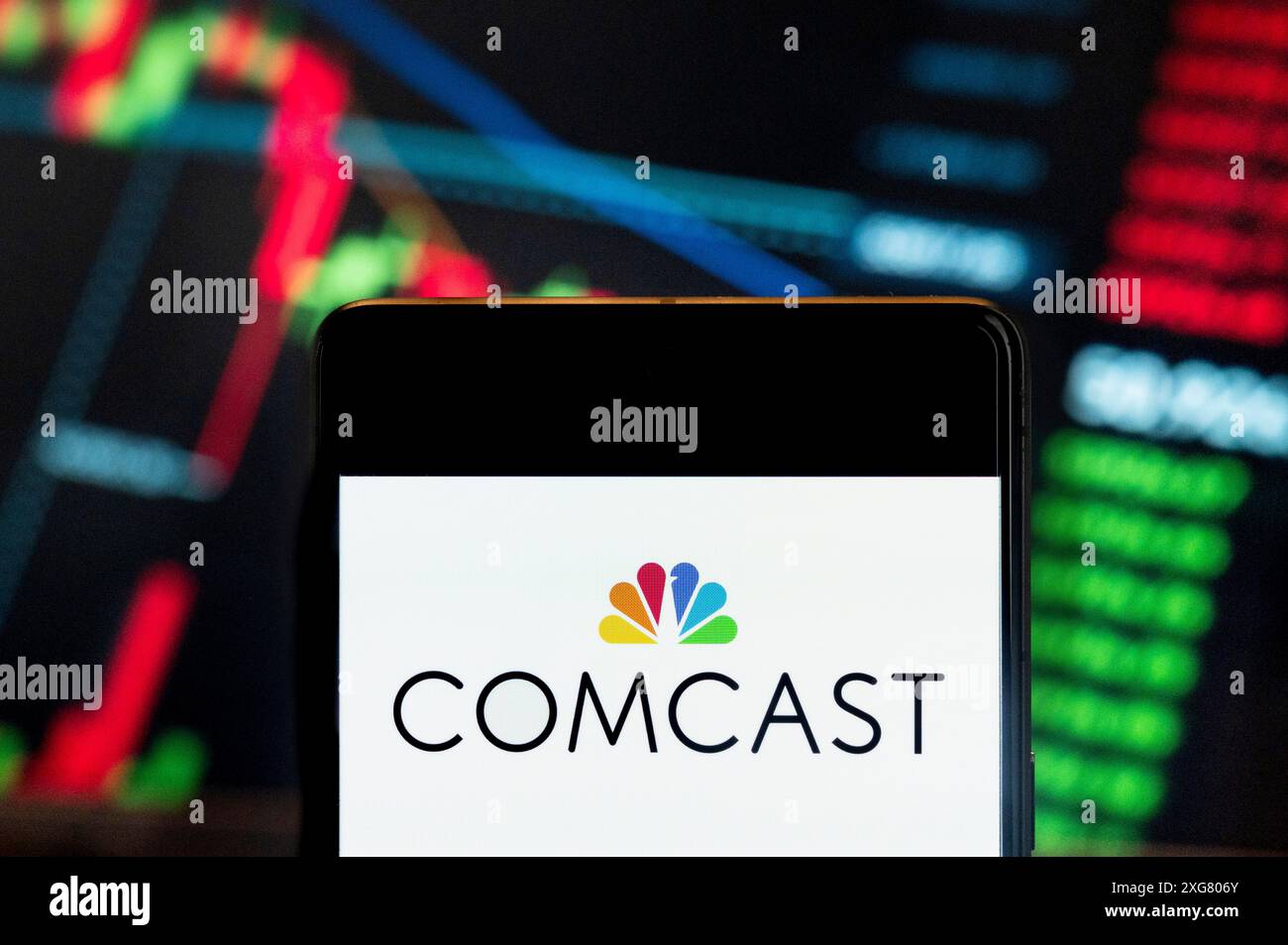 Dans cette illustration photo, le logo du fournisseur de services de télévision sur Internet américain Comcast (NASDAQ : CMCSA) vu affiché sur un smartphone avec un graphique de l'indice boursier économique en arrière-plan. Banque D'Images