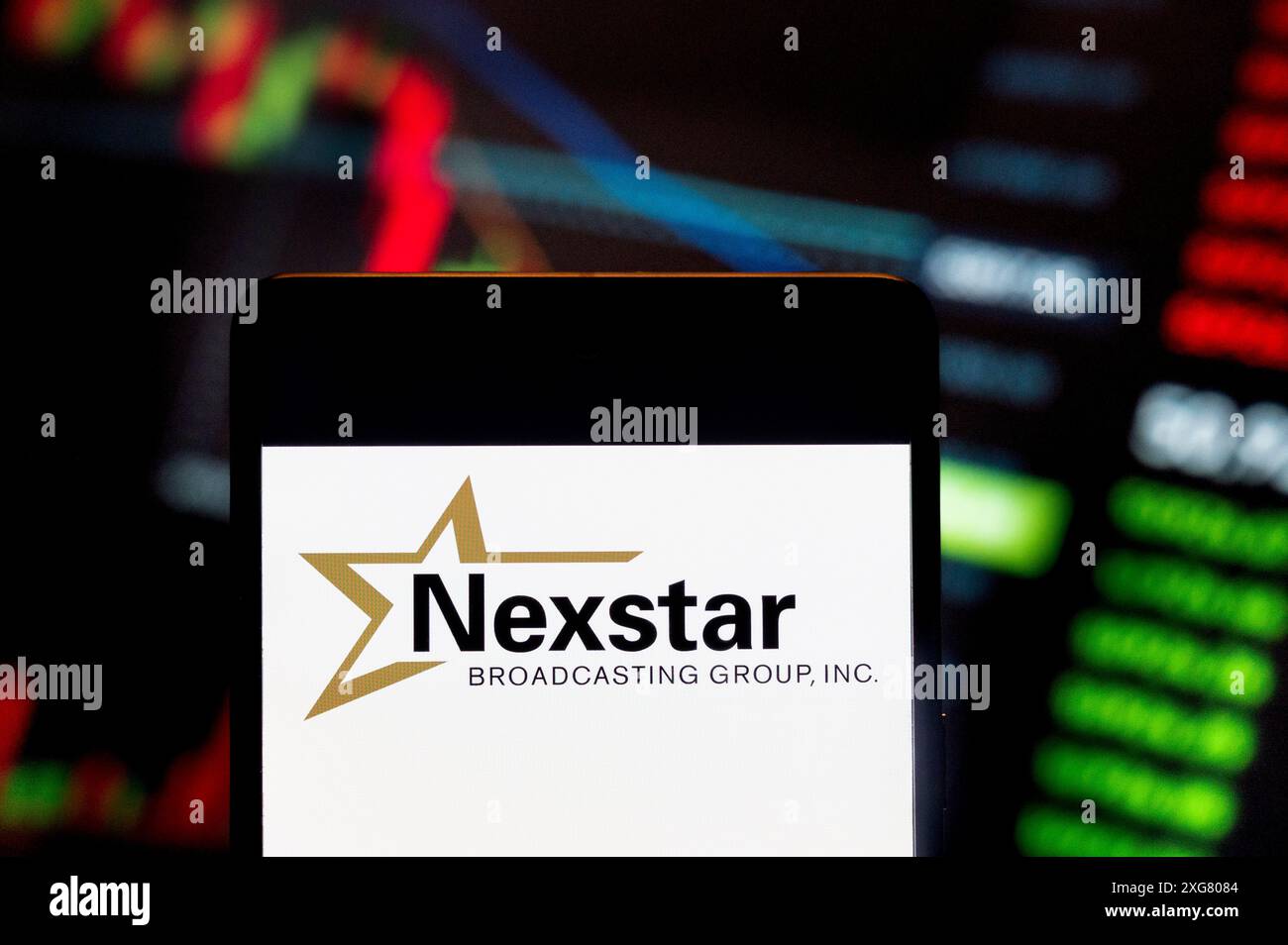 Dans cette illustration photo, la société de médias américaine Nexstar Media Group (NASDAQ : NXST), logo vu affiché sur un smartphone avec un graphique de l'indice boursier économique en arrière-plan. Banque D'Images