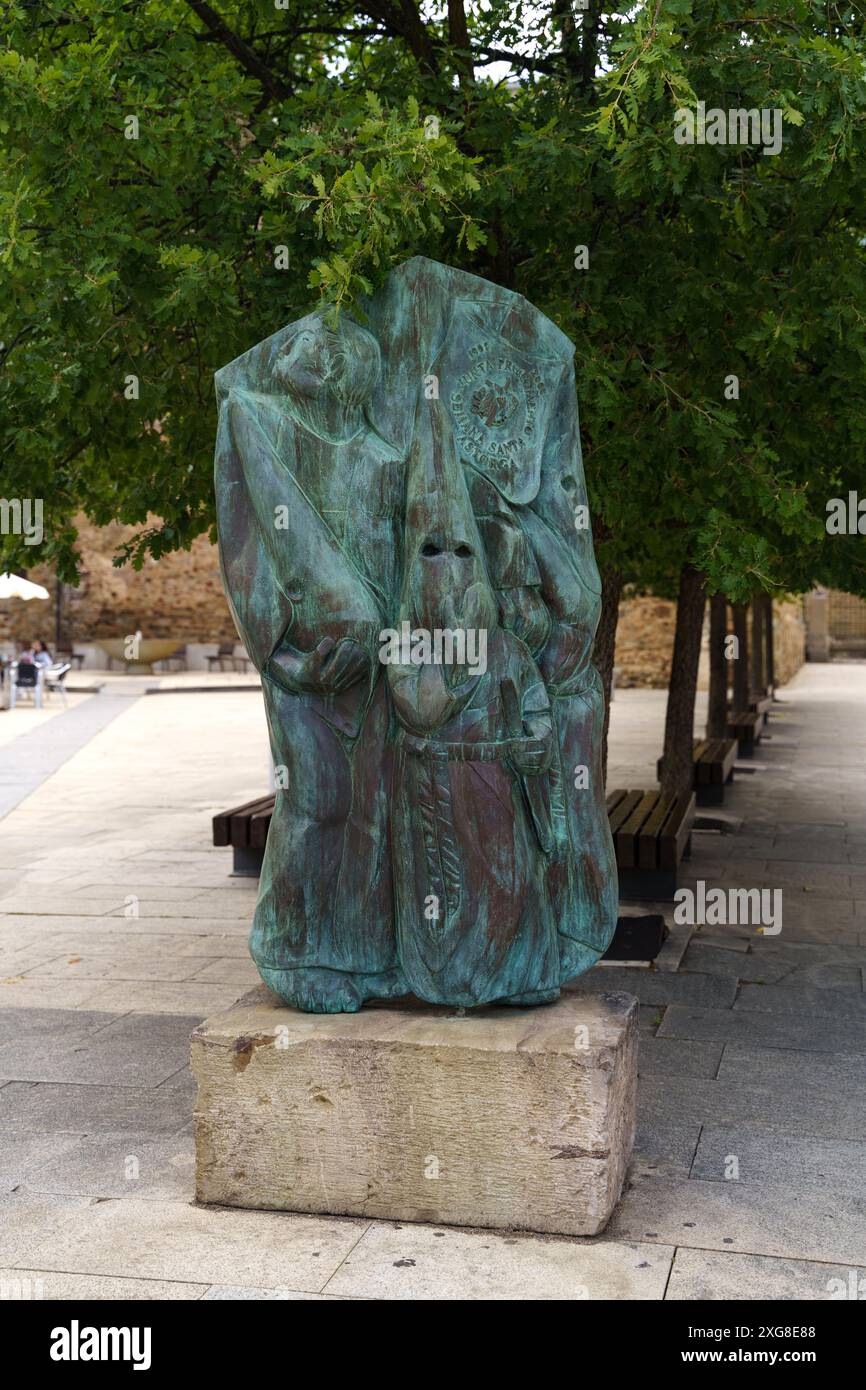 Astorga, Espagne - 4 juin 2023 : sculpture en bronze représentant un groupe de personnages debout sur une base de pierre, nichée sous l'ombre d'un trône vert luxuriant Banque D'Images