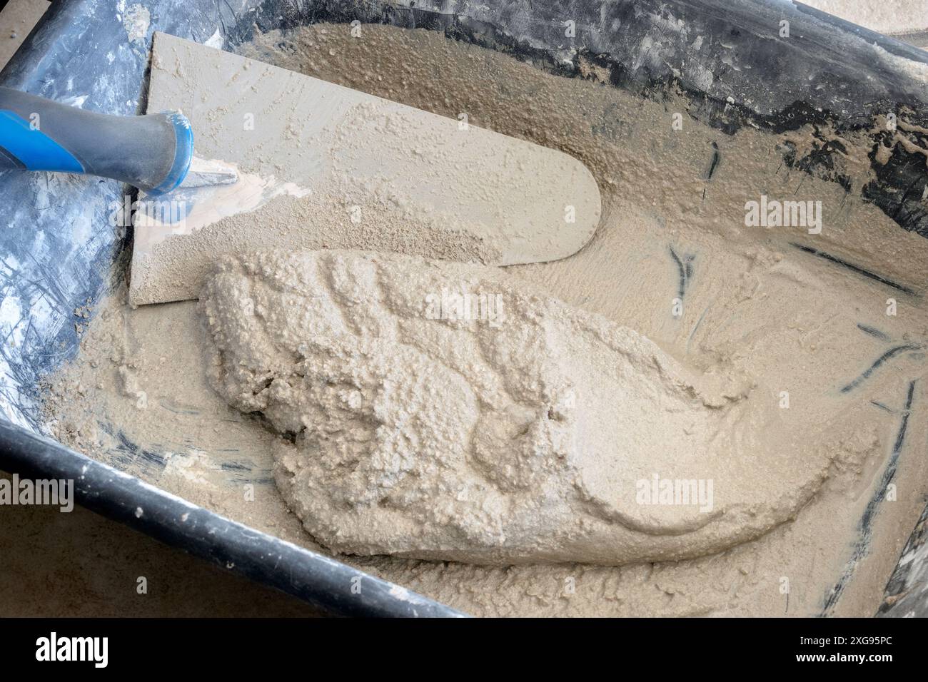 Gros plan du mortier fraîchement mélangé avec une truelle dans une auge en plastique. Banque D'Images