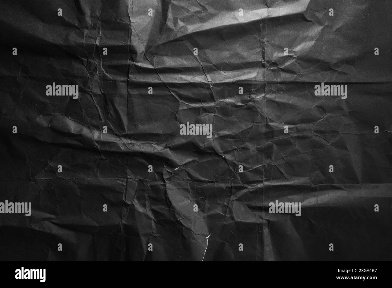 Texture de papier froissé noir dramatique dans un fond de faible luminosité Banque D'Images