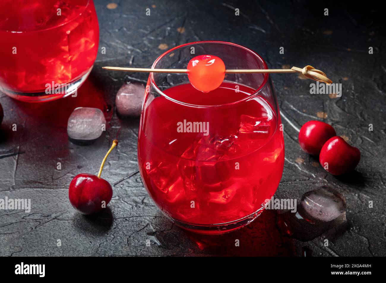 Cocktail de cerise et une queue de maquette sur fond sombre, une boisson rouge vibrante avec glace, sur fond noir Banque D'Images