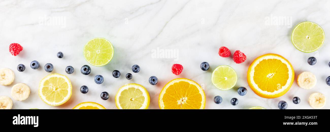 Bannière de menu de produits frais de l'été. Tranches de fruits, prises par le dessus sur un fond de marbre blanc avec un emplacement pour le texte Banque D'Images