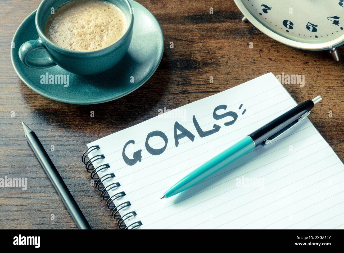 Définition des objectifs. Un bloc-notes avec le mot manuscrit sur un bureau, avec un stylo, un réveil et une tasse de café. Le concept de résolutions et de listes Banque D'Images