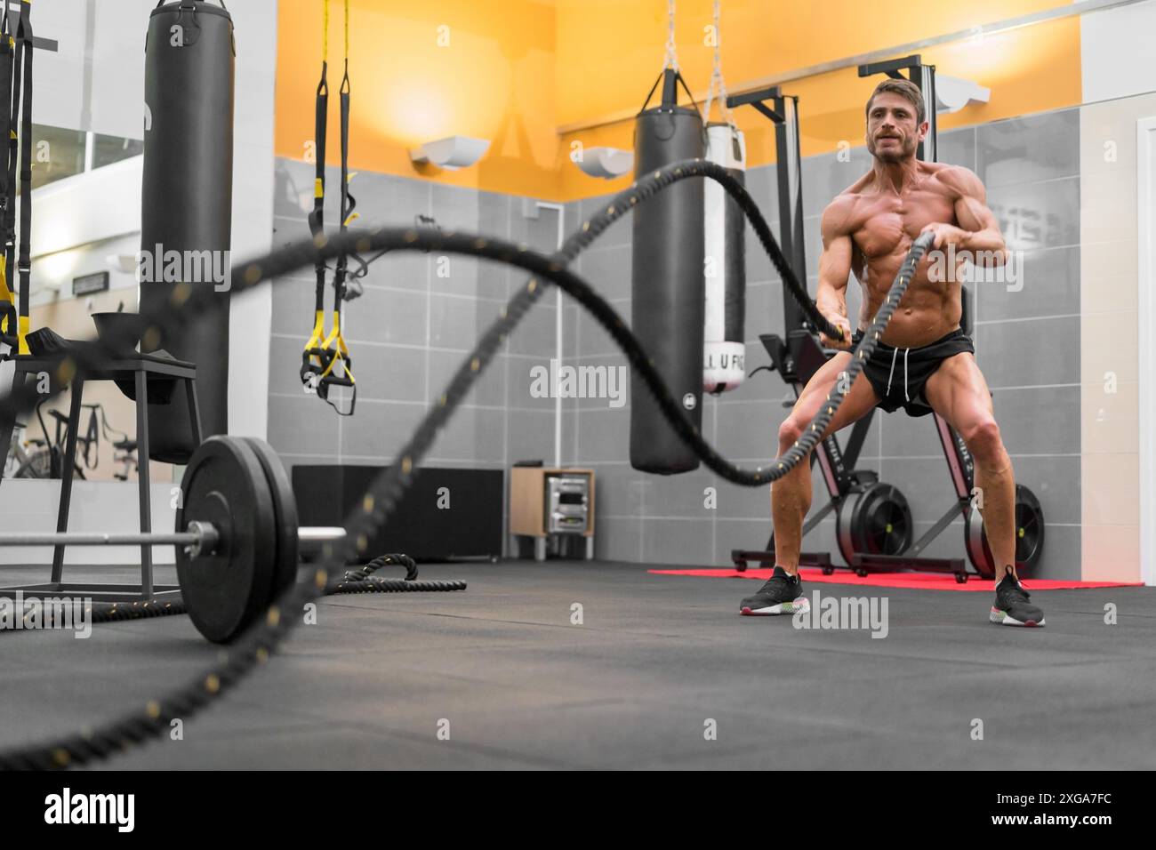 Homme puissant musclé travaillant avec de la corde dans un gymnase de fitness d'entraînement fonctionnel. Photo de haute qualité Banque D'Images
