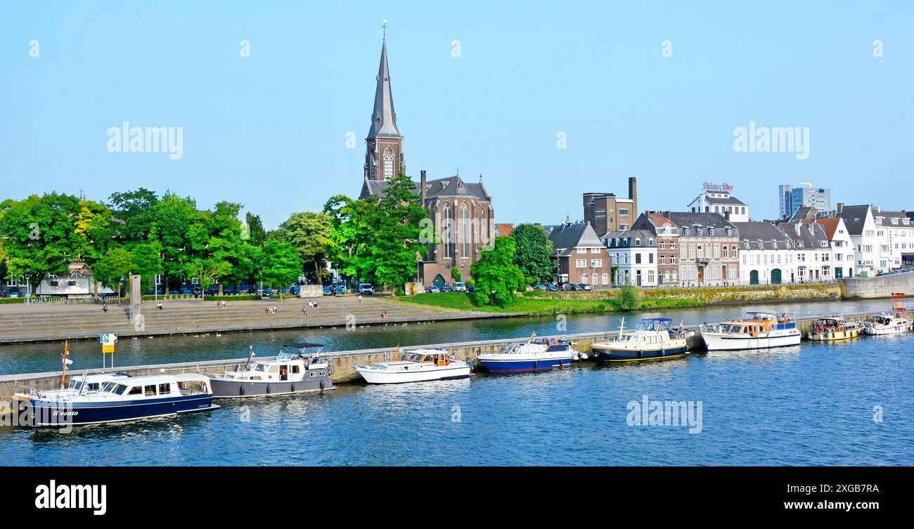 Maastricht River Meuse (maas) et long mur de quai séparant le canal principal de la voie navigable fournit des amarrages pour visiter les bateaux à moteur église de la flèche de l'UE Banque D'Images