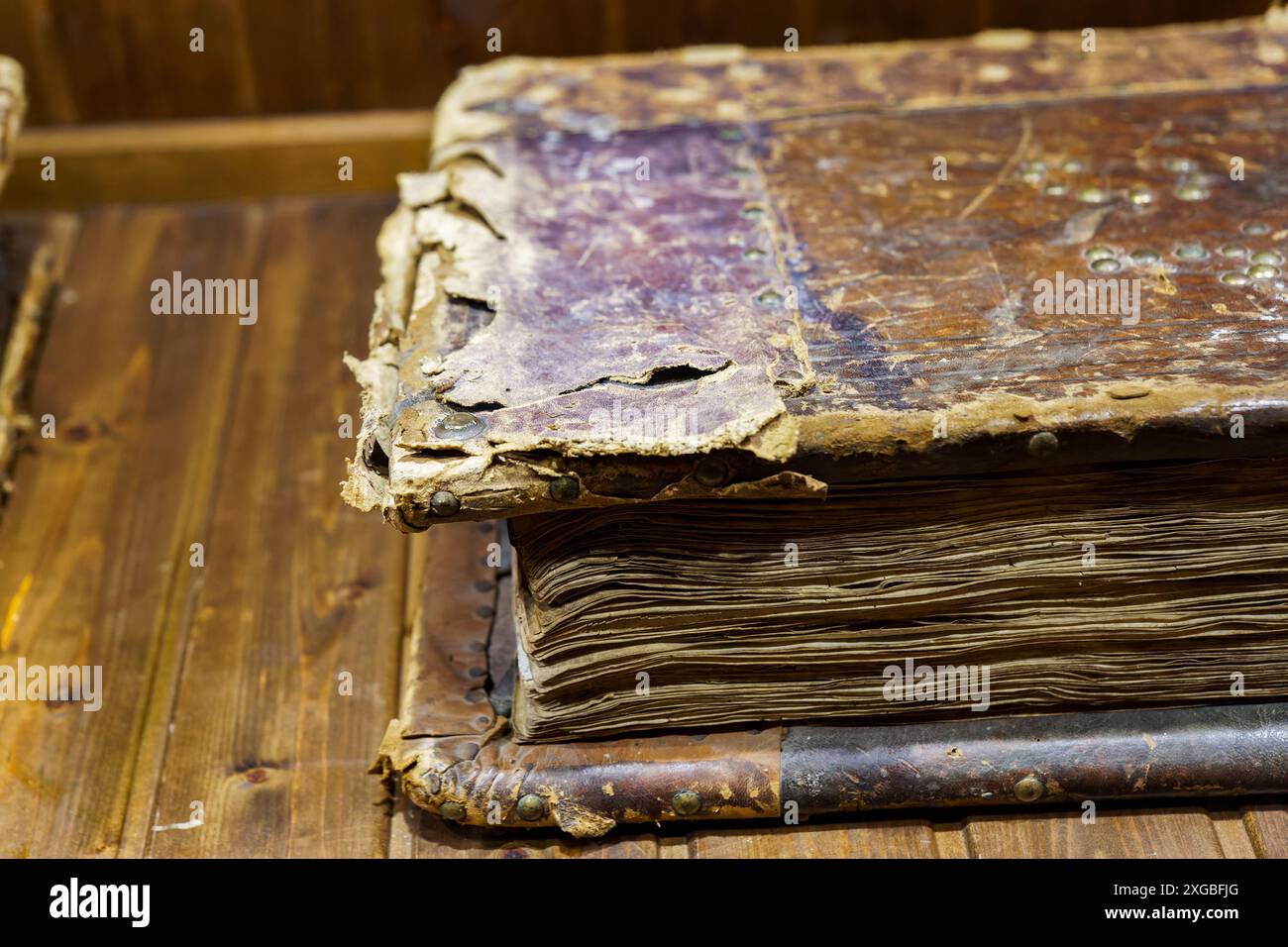 Gros plan d'un vieux livre vieil écrêté avec une couverture en cuir endommagée et des pages jaunies sur une table en bois Banque D'Images