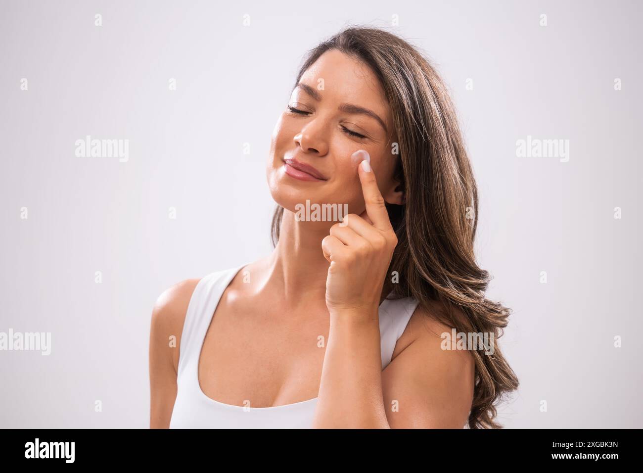 Portrait d'une femme adulte qui applique de la crème pour la peau sur son visage. Banque D'Images