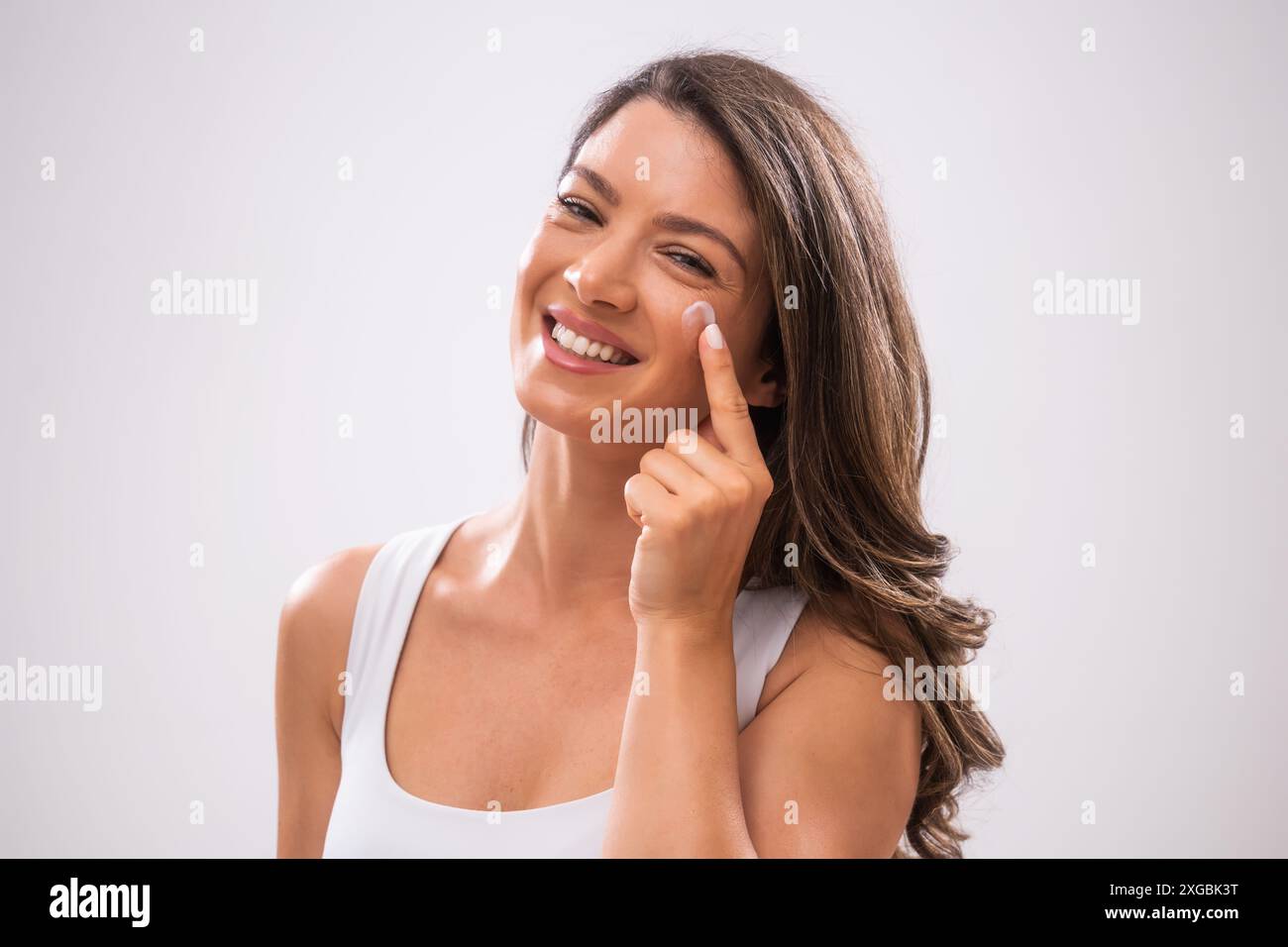 Portrait d'une femme adulte qui applique de la crème pour la peau sur son visage. Banque D'Images