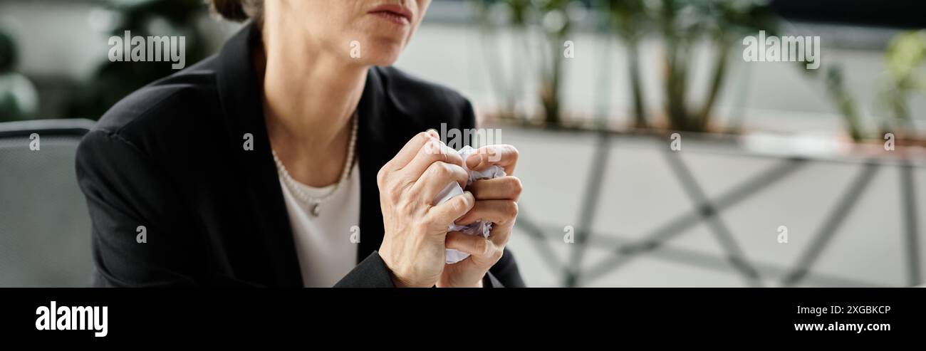 Une femme d’âge moyen s’assoit à une table, expérimentant un moment d’introspection et de contemplation. Banque D'Images
