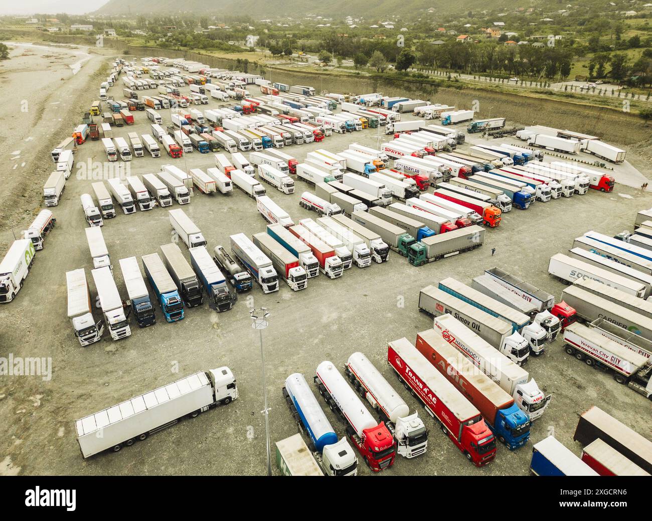 Kazbegi, Géorgie - 7 juillet 2024 : vol aérien au-dessus des lignes de camions se tiennent symétriques dans le parking par Géorgie - Russie frontière populaire militaire Banque D'Images