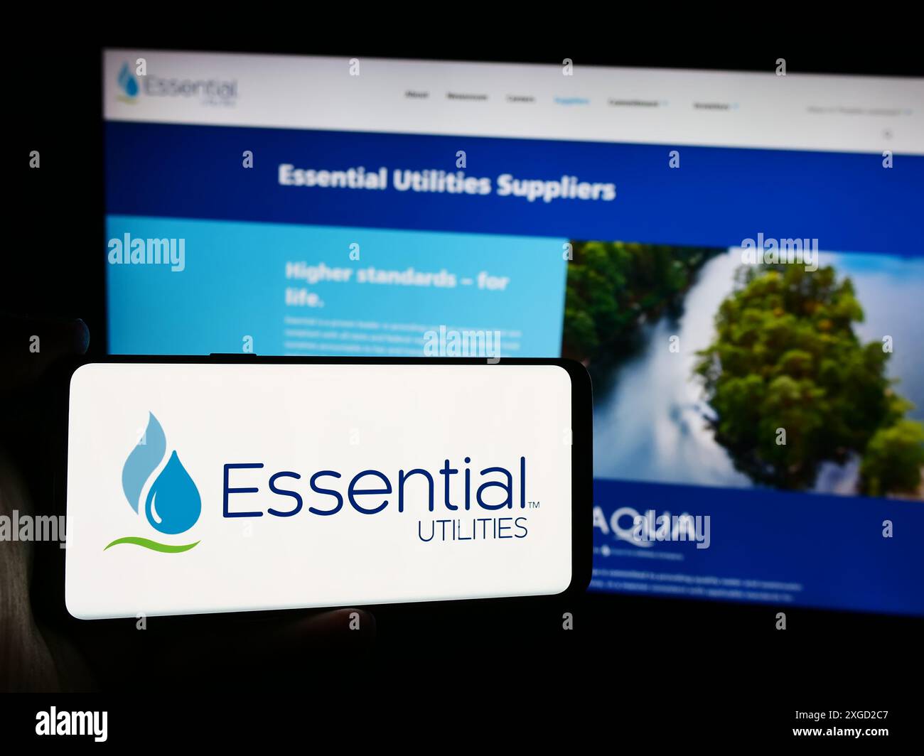 Personne tenant le téléphone portable avec le logo de la société américaine de services publics de l'eau Essential Utilities Inc devant la page web. Concentrez-vous sur l'affichage du téléphone. Banque D'Images
