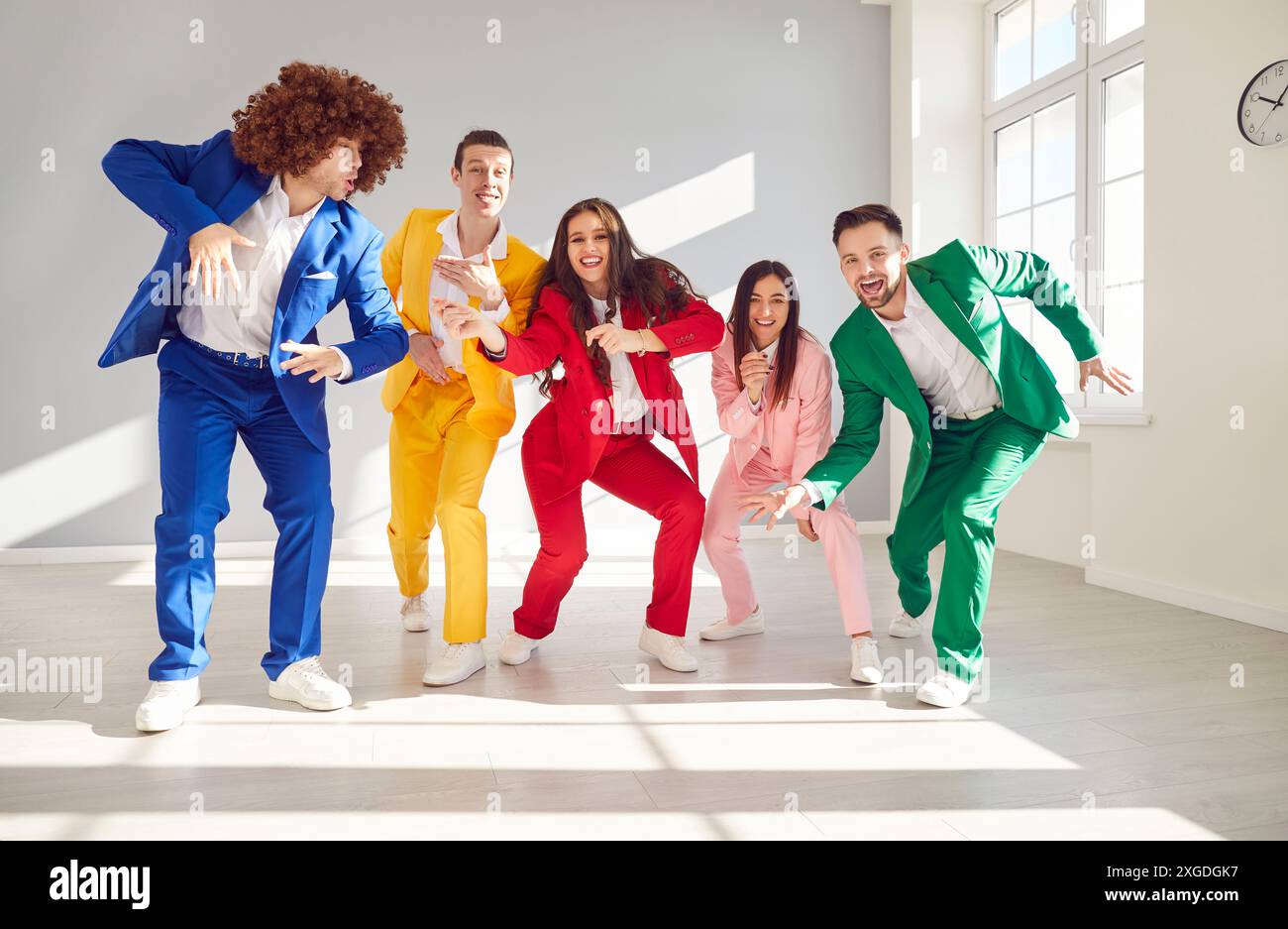 Groupe de personnes élégantes dans les costumes d'affaires colorés Happy Dancing. Groupe de personnes dansant dans des tenues colorées étapes animées à l'atmosphère de piste de danse Banque D'Images