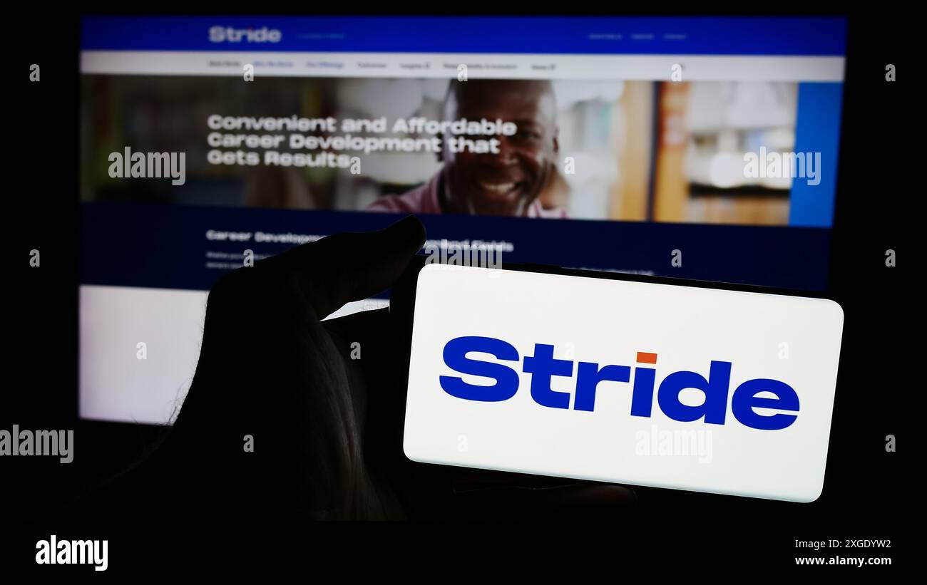 Personne tenant un smartphone avec le logo de la société américaine d'éducation en ligne Stride Inc en face du site Web. Concentrez-vous sur l'affichage du téléphone. Banque D'Images