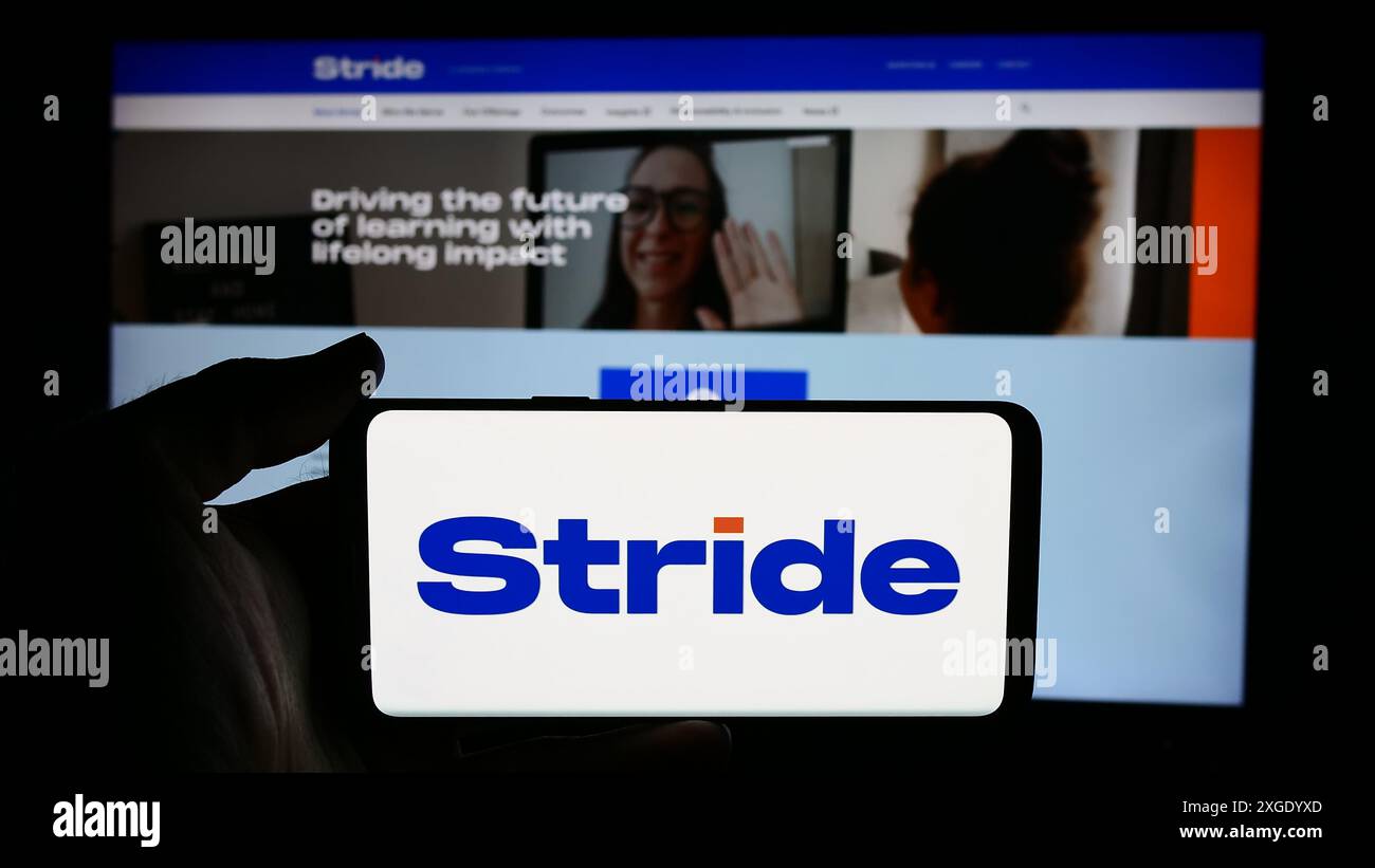 Personne tenant le téléphone portable avec le logo de la société américaine d'éducation en ligne Stride Inc devant la page Web de l'entreprise. Concentrez-vous sur l'affichage du téléphone. Banque D'Images