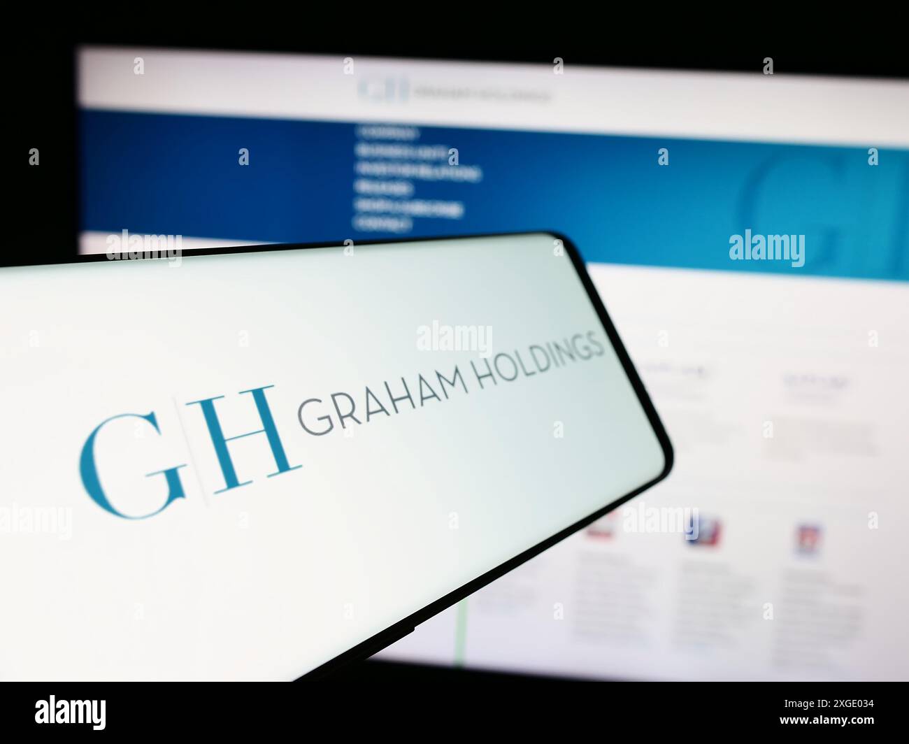Téléphone portable avec le logo de l'entreprise de médias américaine Graham Holdings Company devant le site Web de l'entreprise. Mettez l'accent sur le centre-gauche de l'écran du téléphone. Banque D'Images