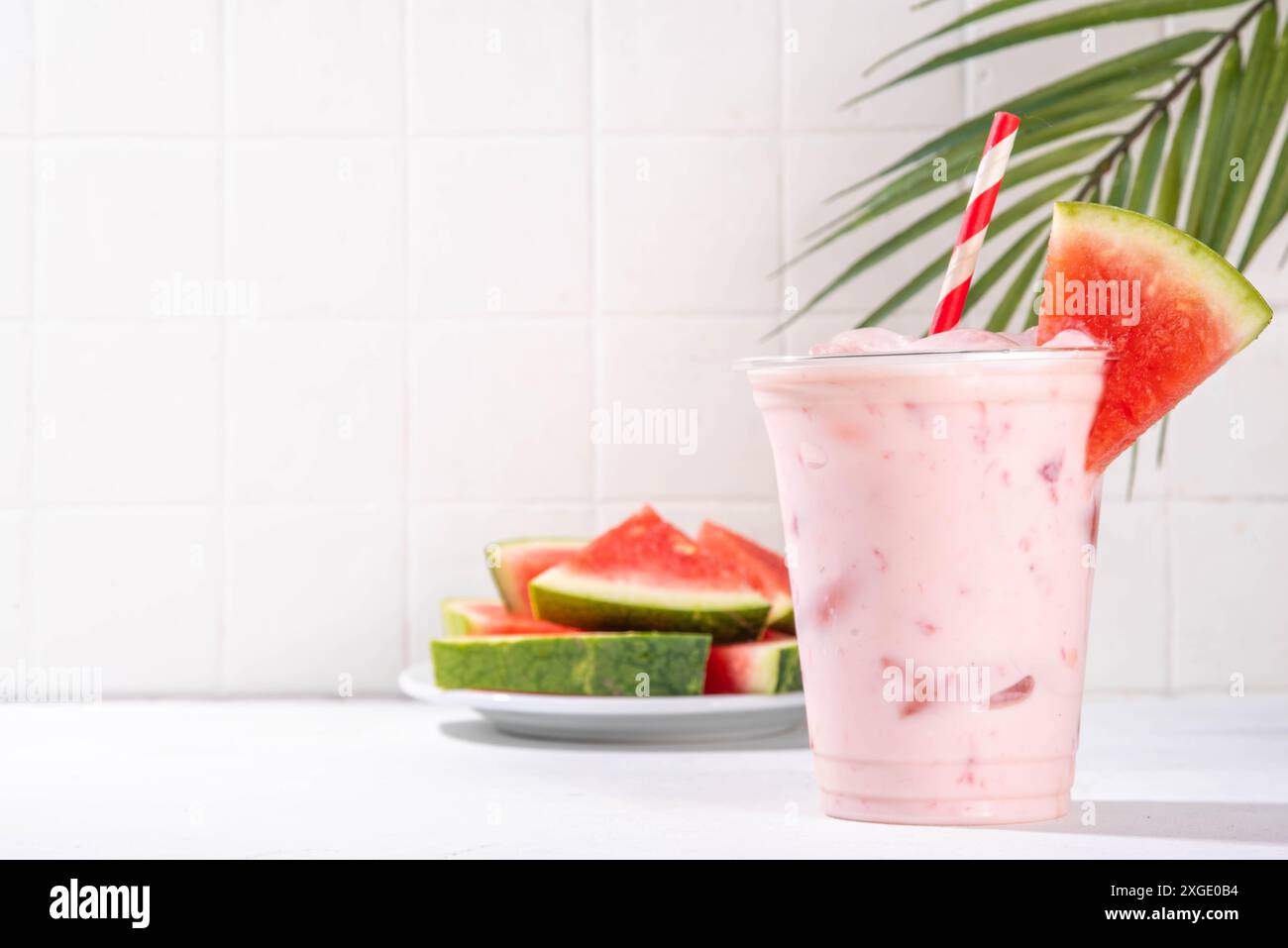 Délicieux milkshake sucré à la pastèque ou cocktail de slushie crémeux, garni de tranche de pastèque dans une tasse en plastique, espace de copie Banque D'Images