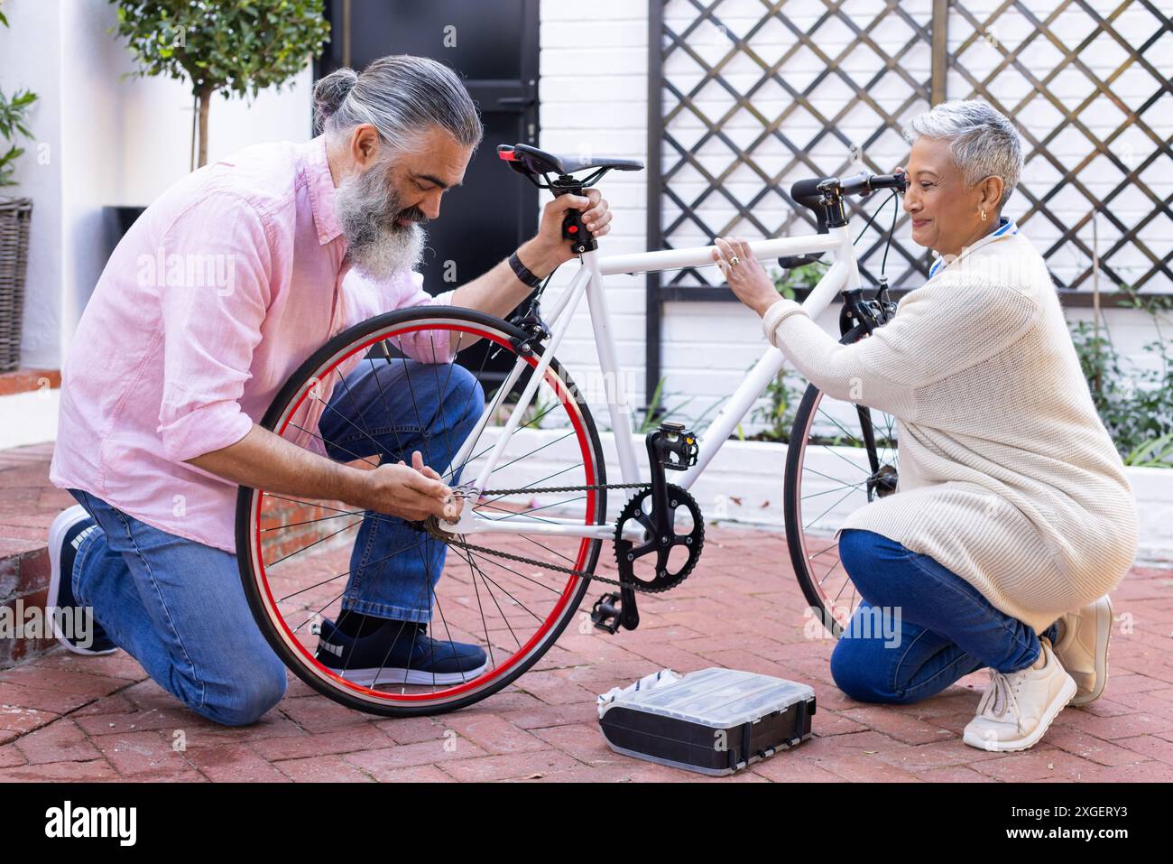 Réparation de vélo ensemble, couple senior profitant de l'activité de plein air dans la cour Banque D'Images