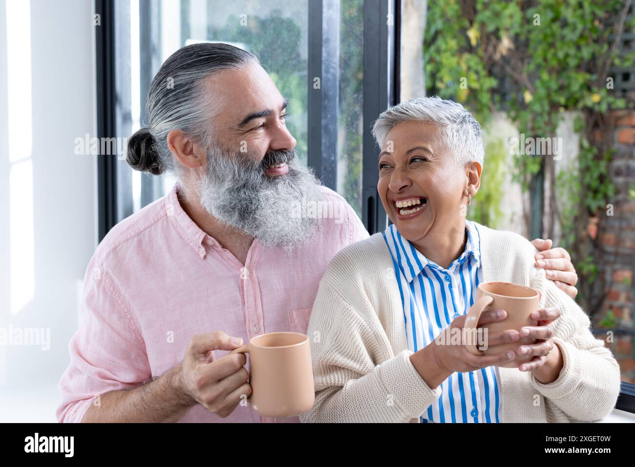 Couple senior souriant profitant d'un café ensemble, partageant un moment joyeux à l'intérieur Banque D'Images