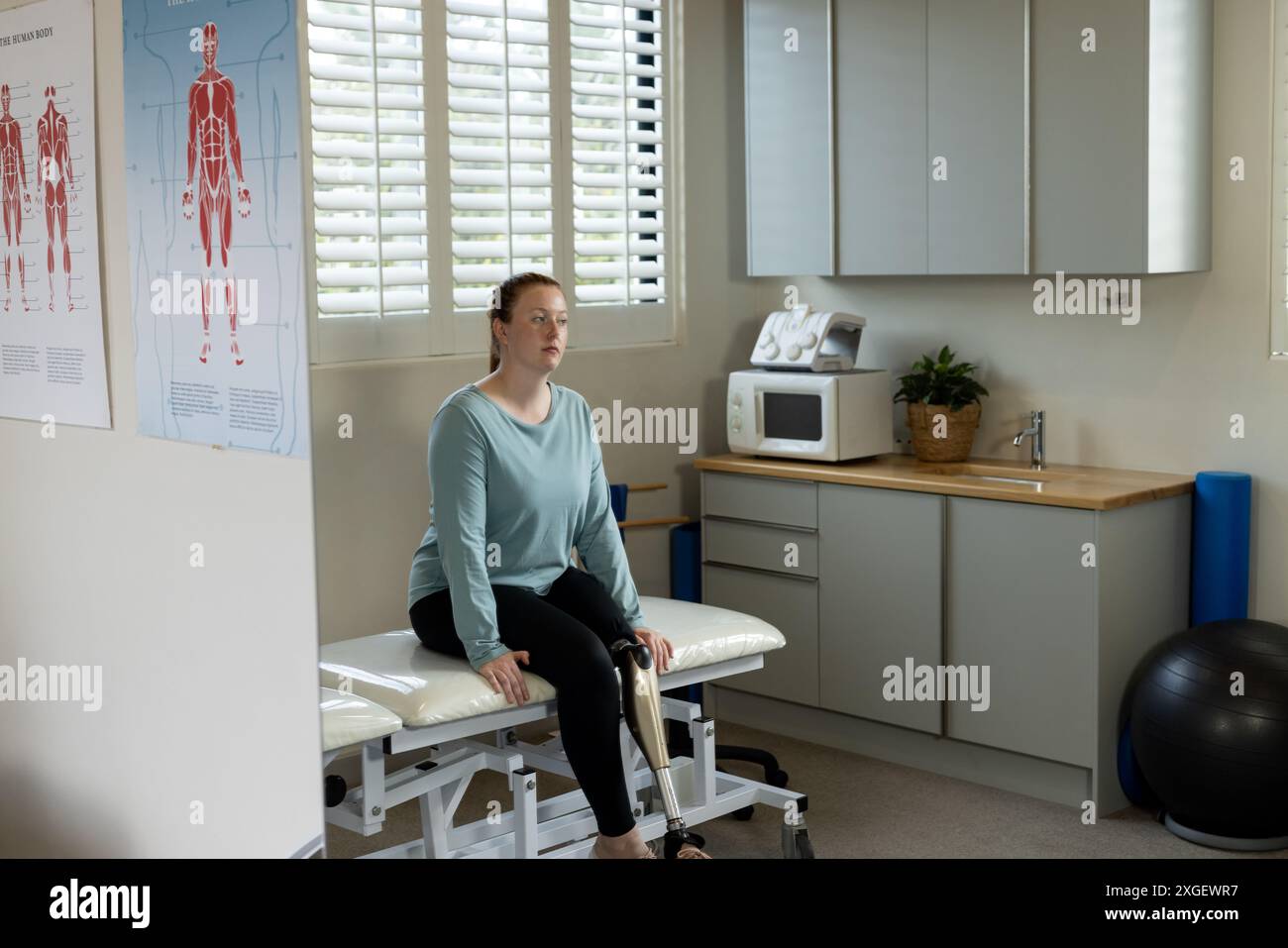 Femme avec une jambe prothétique assise sur la table d'examen dans la clinique médicale médicale, espace de copie Banque D'Images