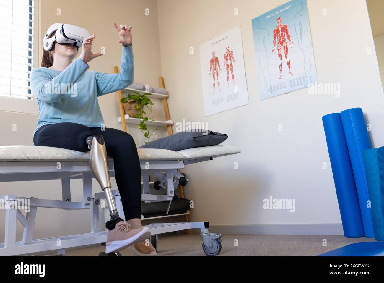 En utilisant le casque VR, femme avec la jambe prothétique assise sur la table d'examen médical, espace de copie Banque D'Images