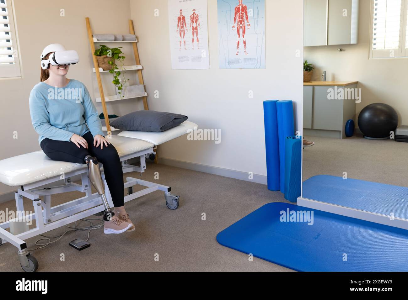 Femme dans la jambe prothétique utilisant un casque VR tout en étant assis sur la table d'examen médical, copiez l'espace Banque D'Images