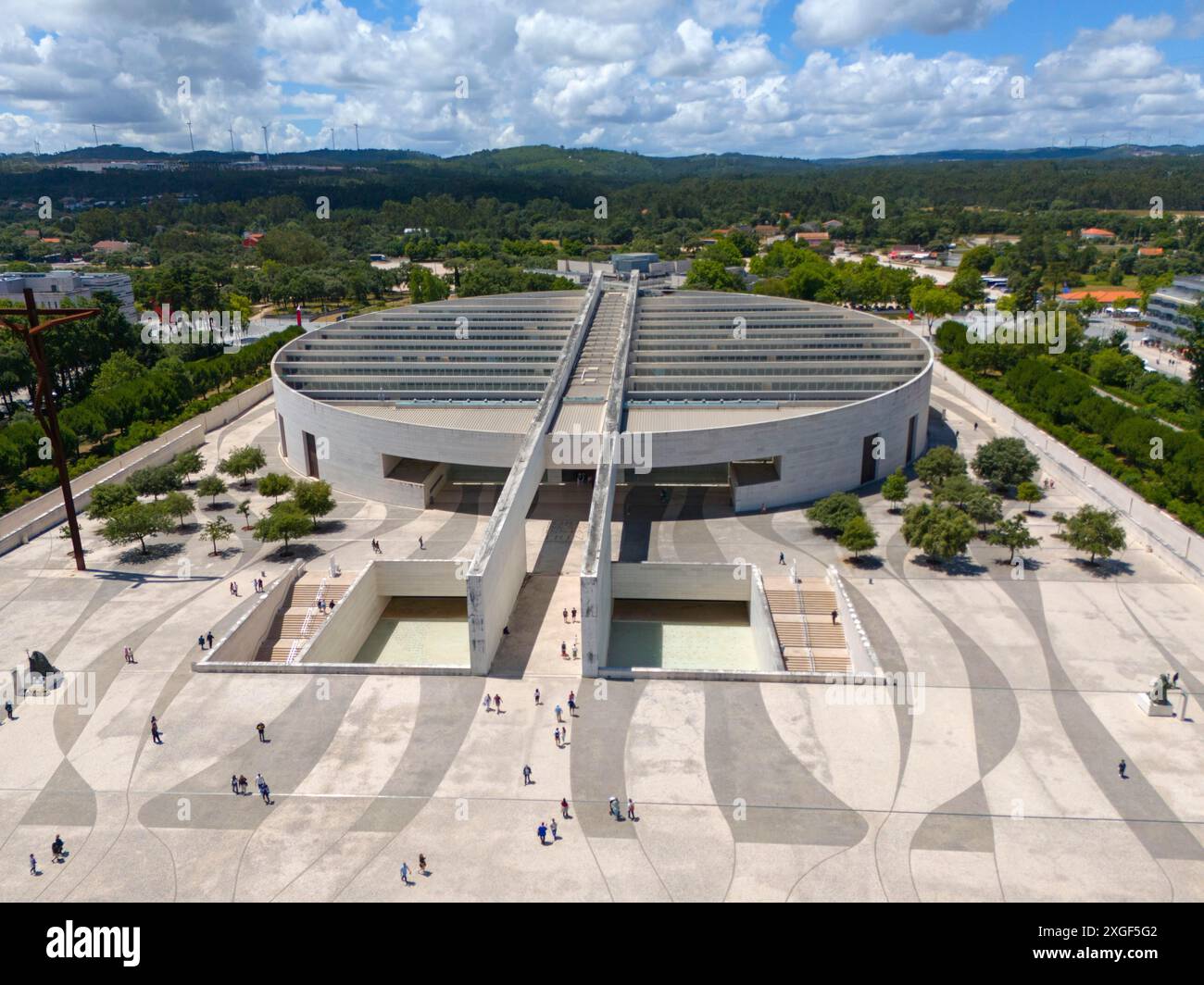 Architecture moderne avec une grande place et des gens, entouré d'arbres et de forêts, sous un ciel nuageux, vue aérienne, Basilique du très Saint Banque D'Images