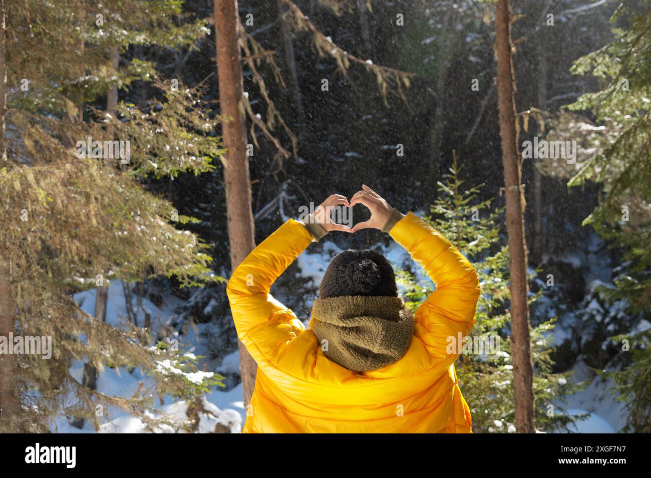 Portrait de dos jeune femme caucasienne et montre des doigts geste de coeur, amour au niveau des yeux. Vue arrière dans la forêt et les montagnes. Vue arrière Banque D'Images