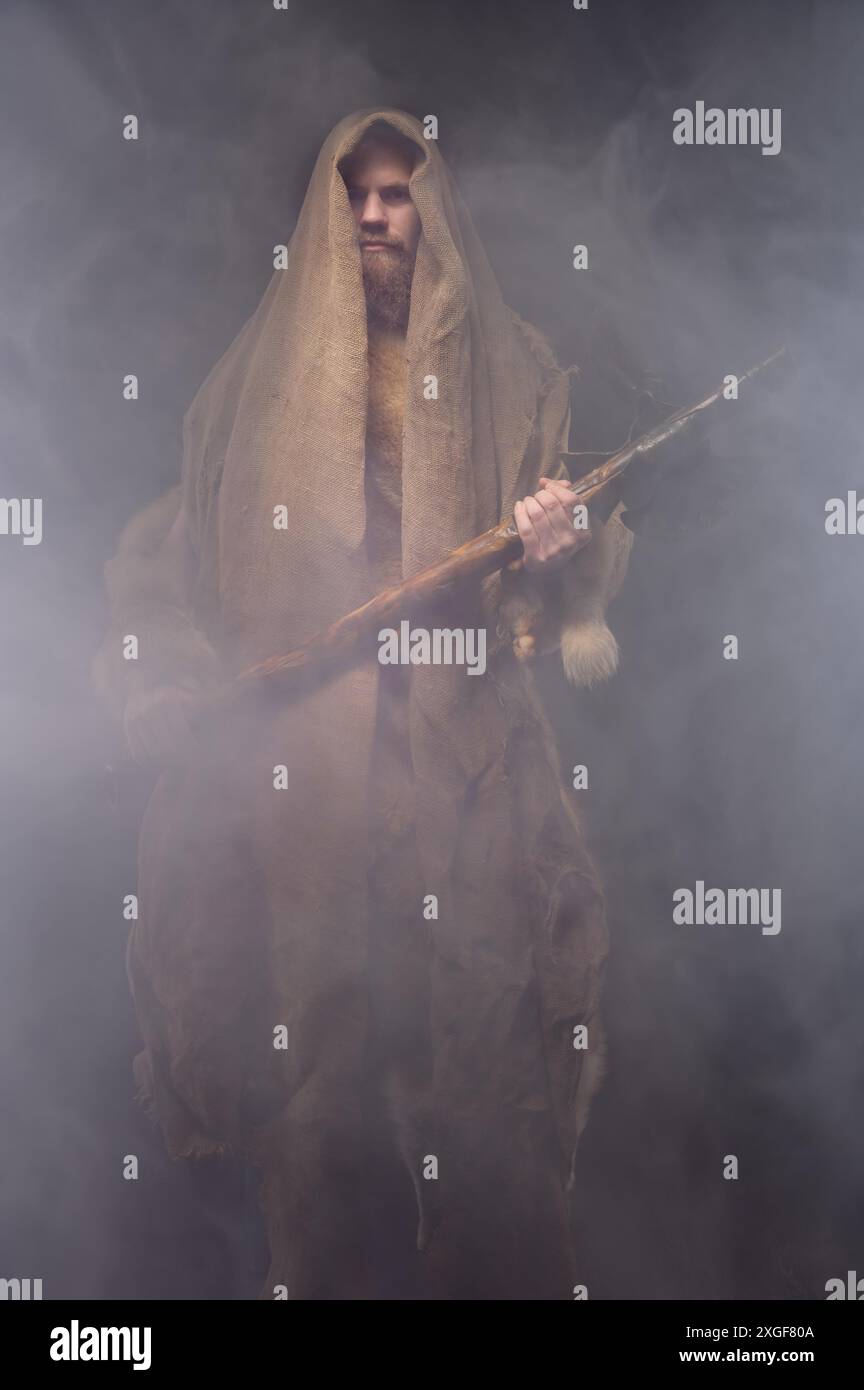 Un homme dans un costume de moine vintage avec une hache en bois dans une brume, cosplay pour les temps anciens, une intrigue historique Banque D'Images