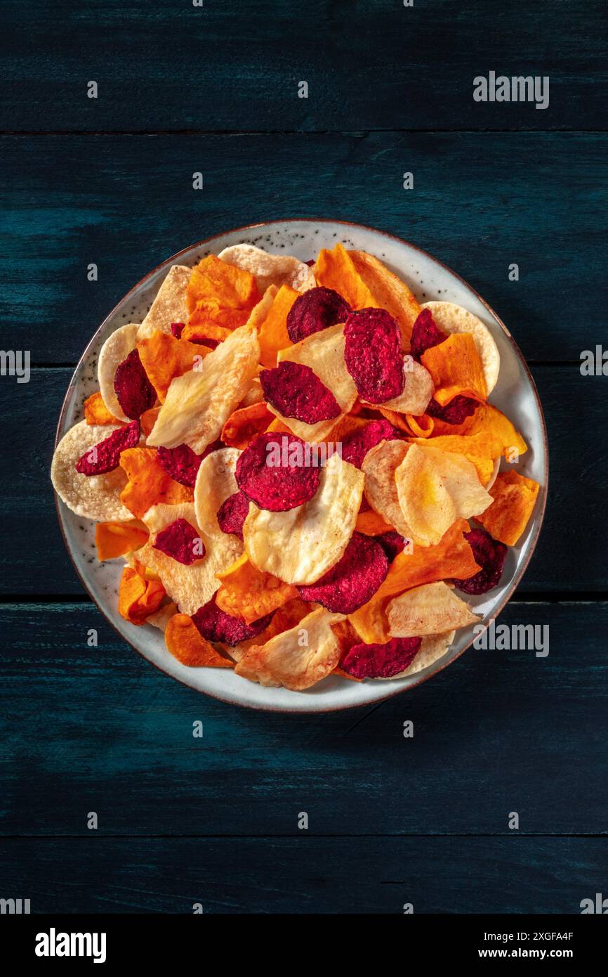 Chips de légumes, tiré du dessus, une collation végétalienne saine sur une table en bois sombre Banque D'Images