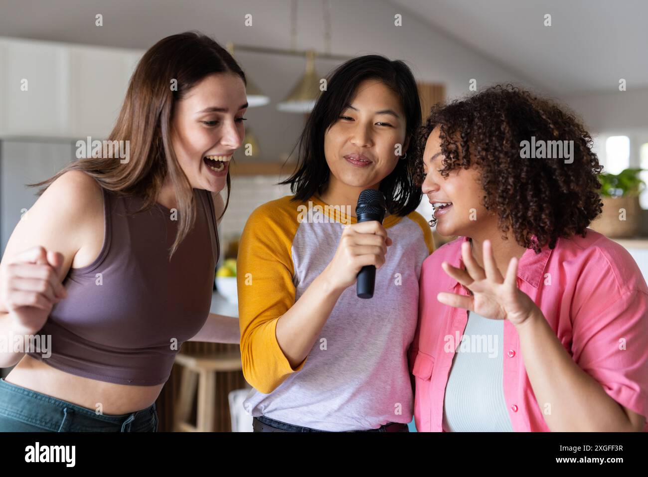 Chanter karaoké, trois amies femmes profitant du temps ensemble à la fête à la maison Banque D'Images