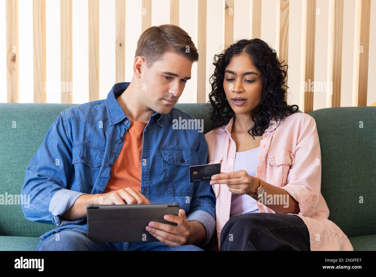 En utilisant la tablette, jeune couple effectuant le paiement en ligne avec la carte de crédit sur le canapé Banque D'Images En utilisant la tablette, jeune couple effectuant le paiement en ligne avec la carte de crédit sur le canapé Banque D'Images