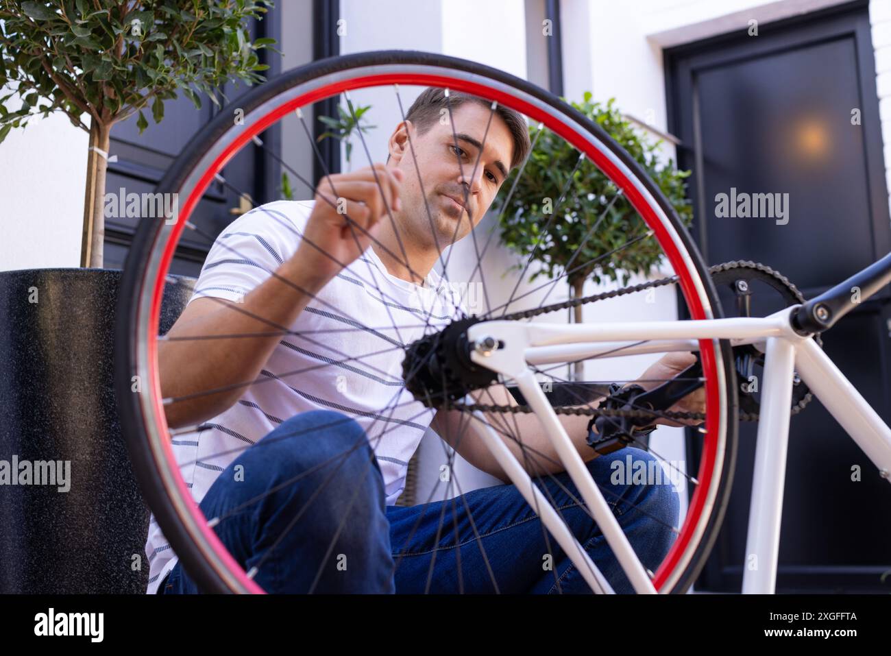 Réparation de bicyclette, homme ajustant les rayons de roue à l'extérieur, en se concentrant sur l'entretien Banque D'Images