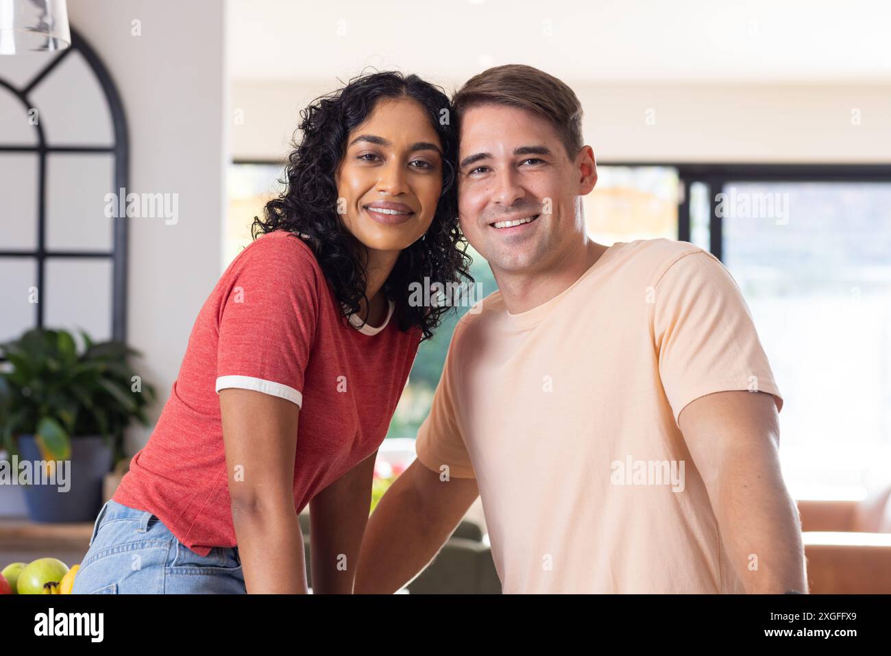 Posant ensemble, couple souriant dans un environnement de maison confortable Banque D'Images