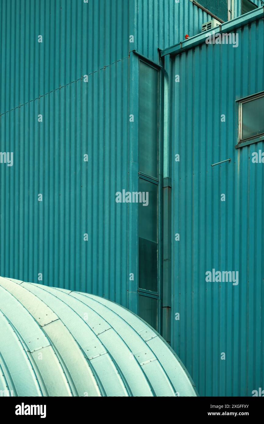 Bâtiment d'entrepôt en métal courbé comme fond architectural abstrait. Mur en métal ondulé en arrière-plan, illustrant l'architecture industrielle. Banque D'Images