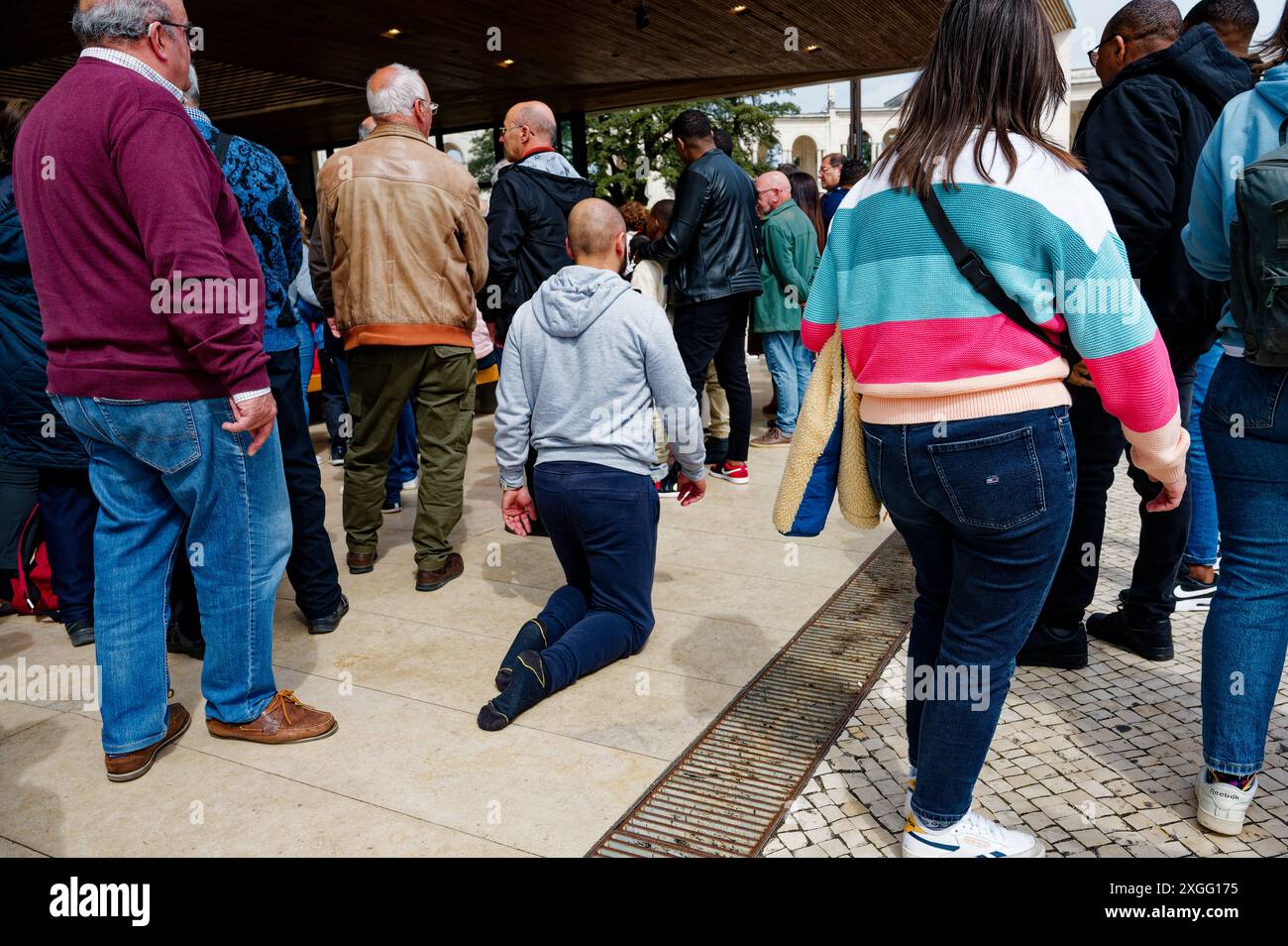 Homme chauve d'âge moyen alors qu'il rampait sur ses genoux à travers la foule à l'extérieur de la chapelle des apparitions Banque D'Images