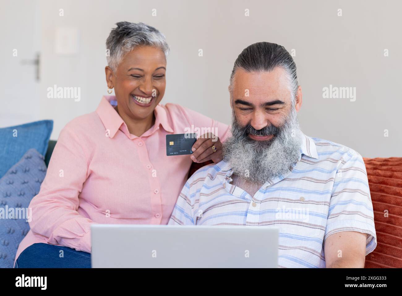 En utilisant un ordinateur portable et en tenant une carte de crédit, couple senior magasinant en ligne, souriant ensemble Banque D'Images En utilisant un ordinateur portable et en tenant une carte de crédit, couple senior magasinant en ligne, souriant ensemble Banque D'Images