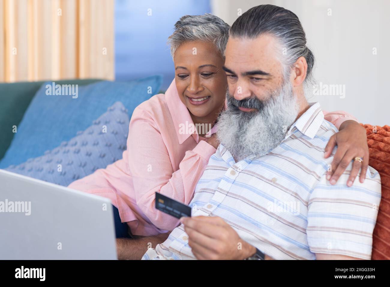 Couple senior shopping en ligne avec carte de crédit et ordinateur portable, assis sur le canapé Banque D'Images Couple senior shopping en ligne avec carte de crédit et ordinateur portable, assis sur le canapé Banque D'Images