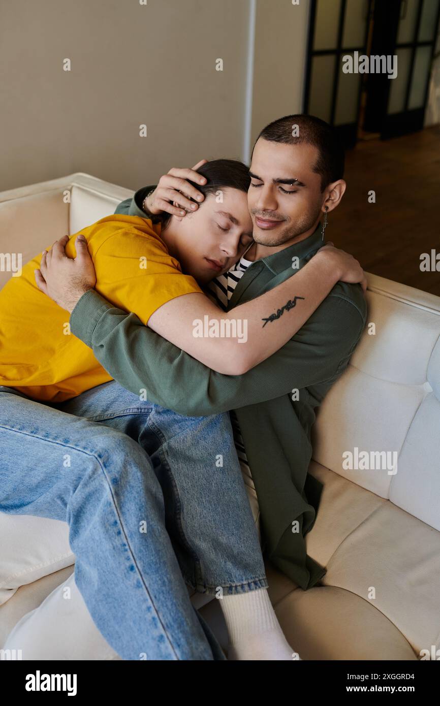 Un jeune couple gay se câlin sur un canapé dans un appartement moderne. Banque D'Images
