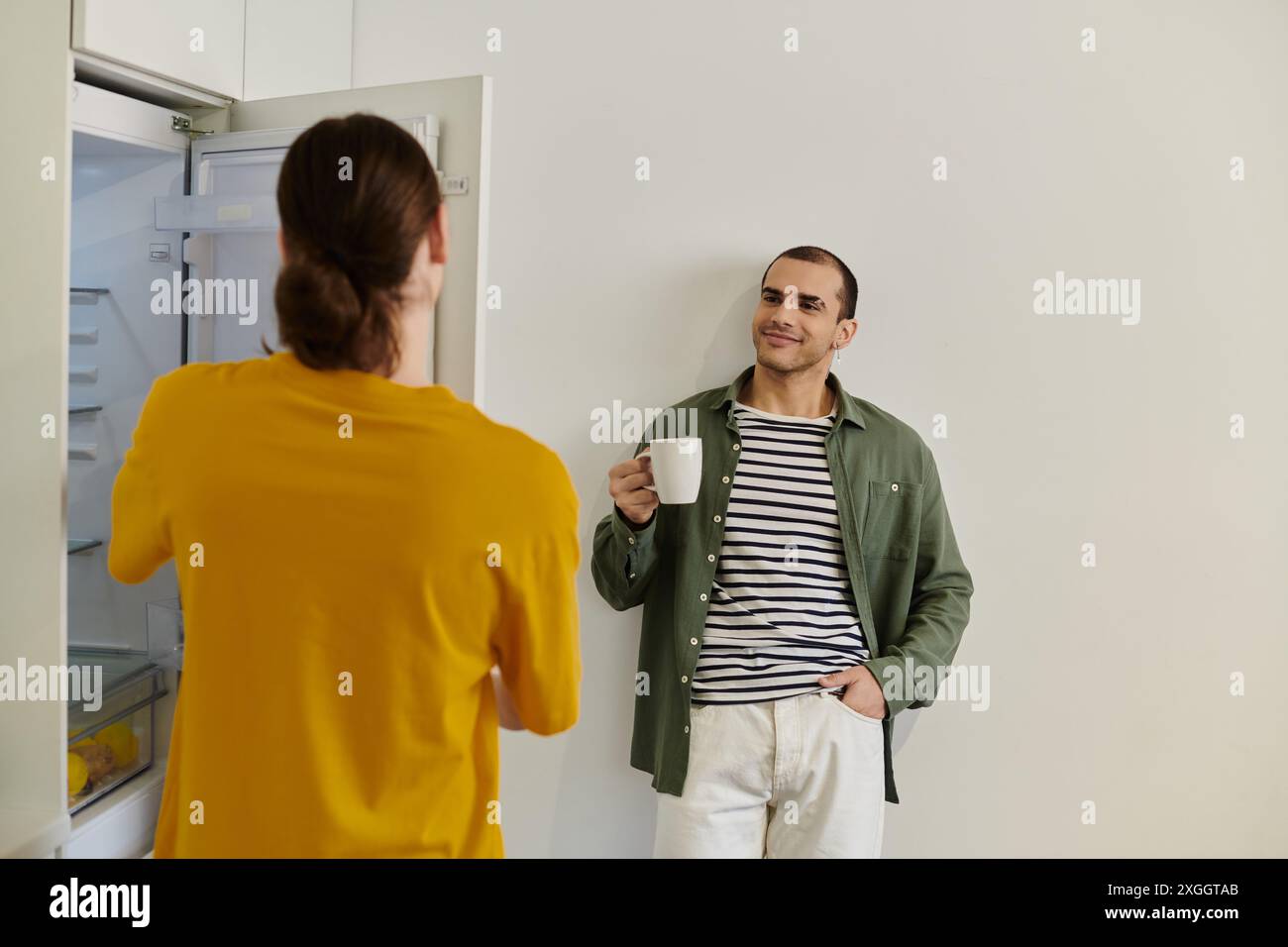 Un jeune couple gay en tenue décontractée profitant d'un moment de calme ensemble dans leur appartement moderne. Banque D'Images