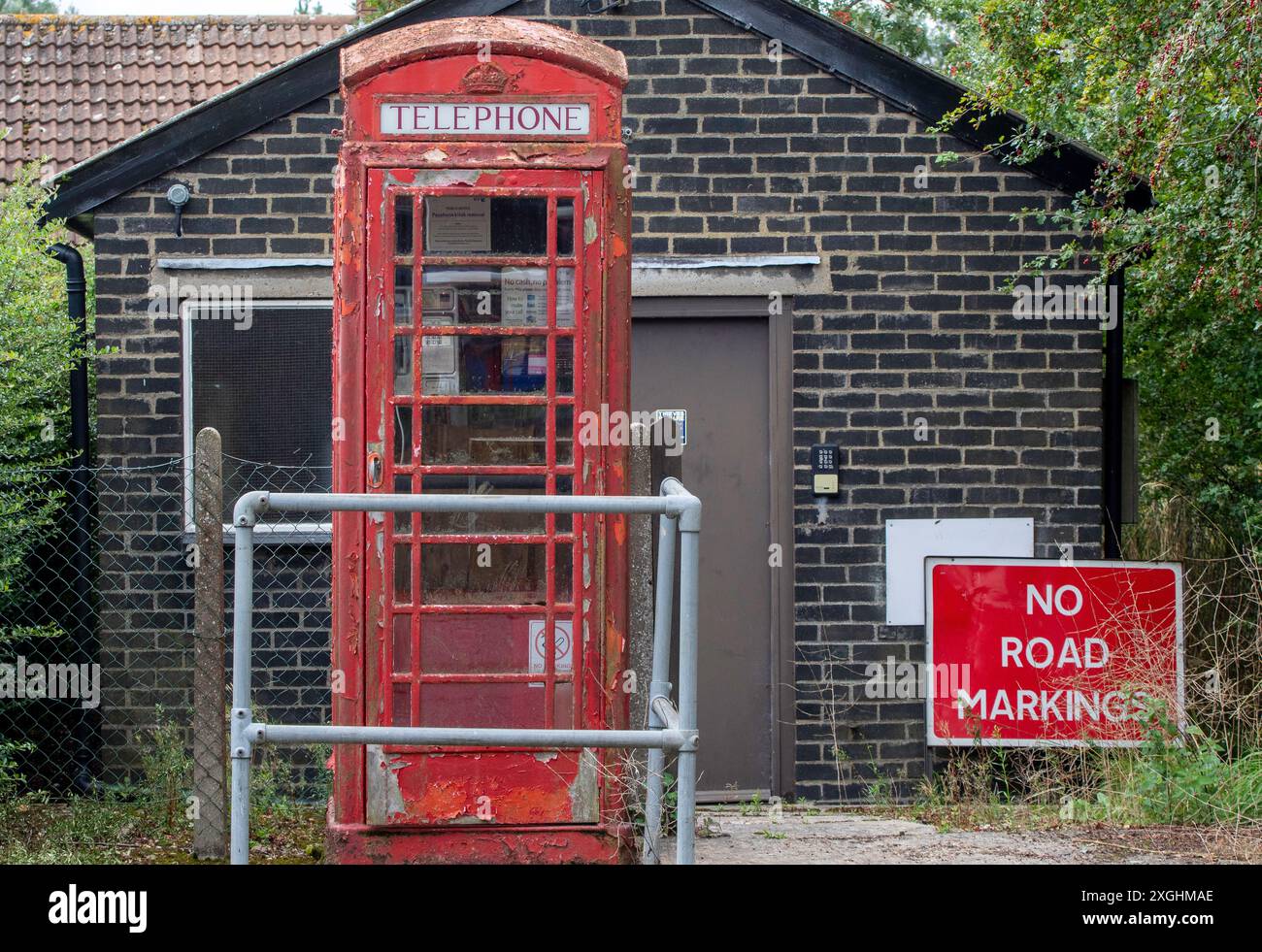 Une cabine téléphonique rouge publique dans un village du Suffolk apparemment oublié par les télécoms britanniques à en juger par la peinture écaillée et le mauvais état de réparation Banque D'Images